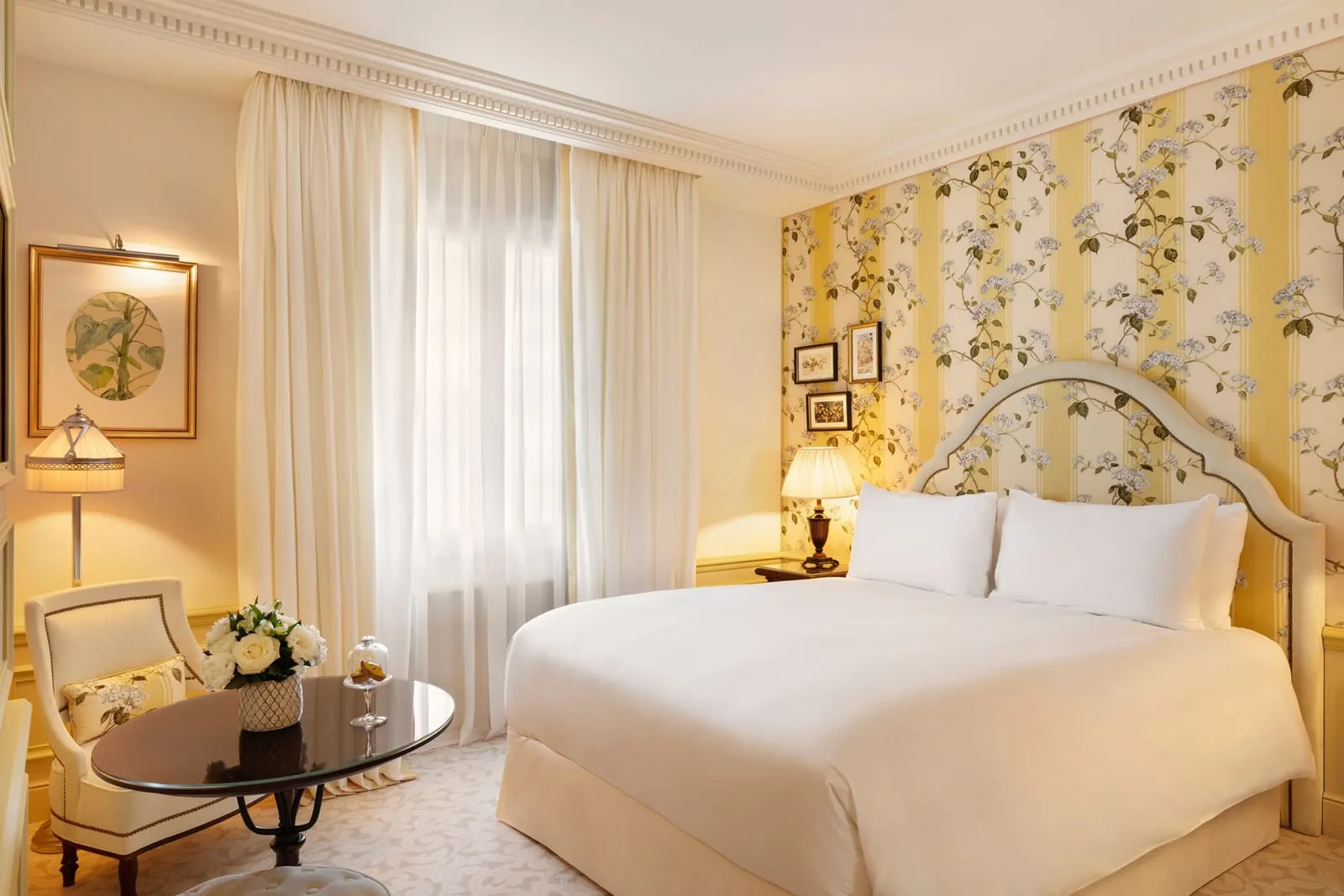 Deluxe Premium Room at Hôtel Métropole Monte-Carlo: the bed against yellow floral wallpaper, with a round table and an armchair