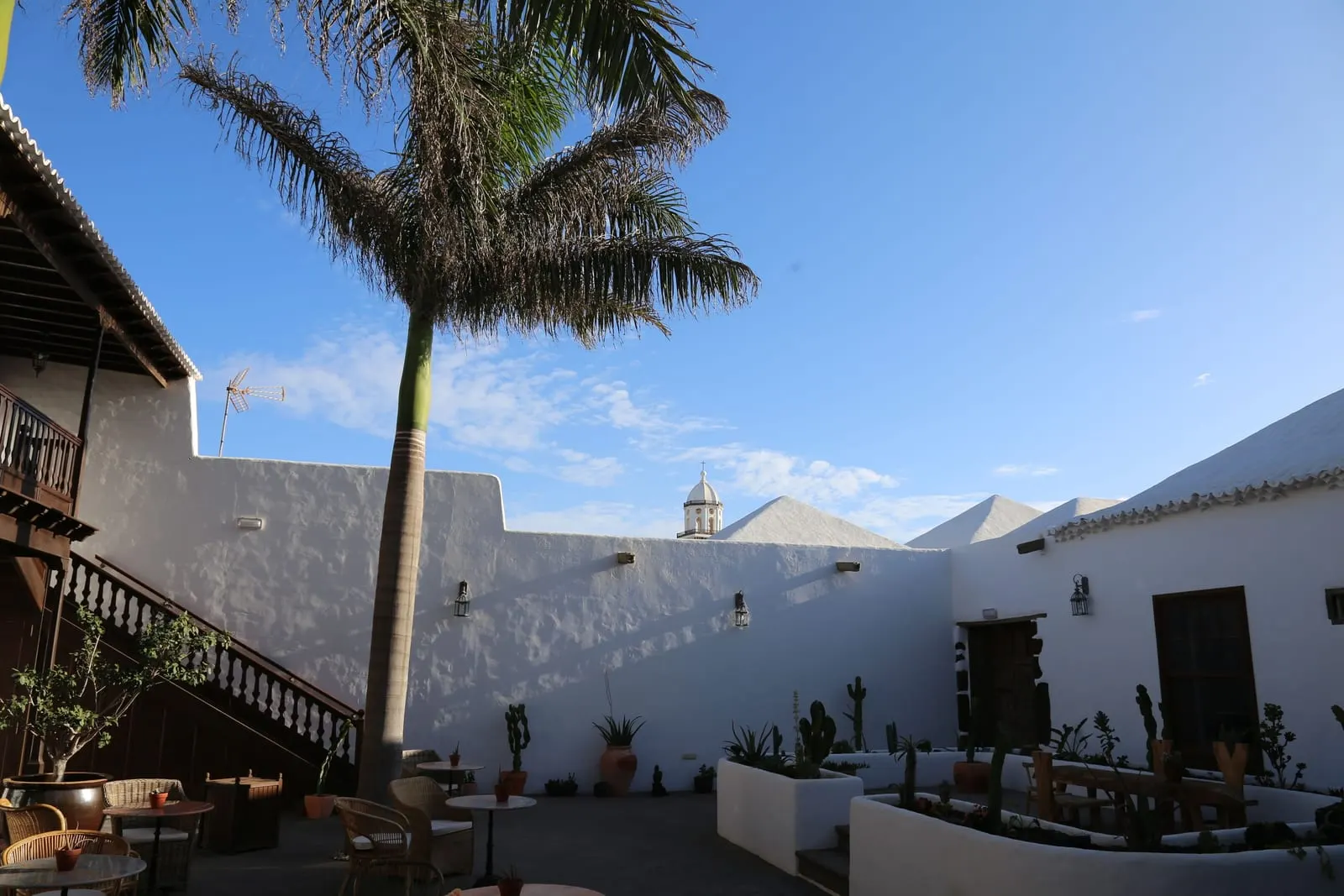 Hotel Boutique Palacio Ico: A church tower beyond the whitewashed courtyard wall