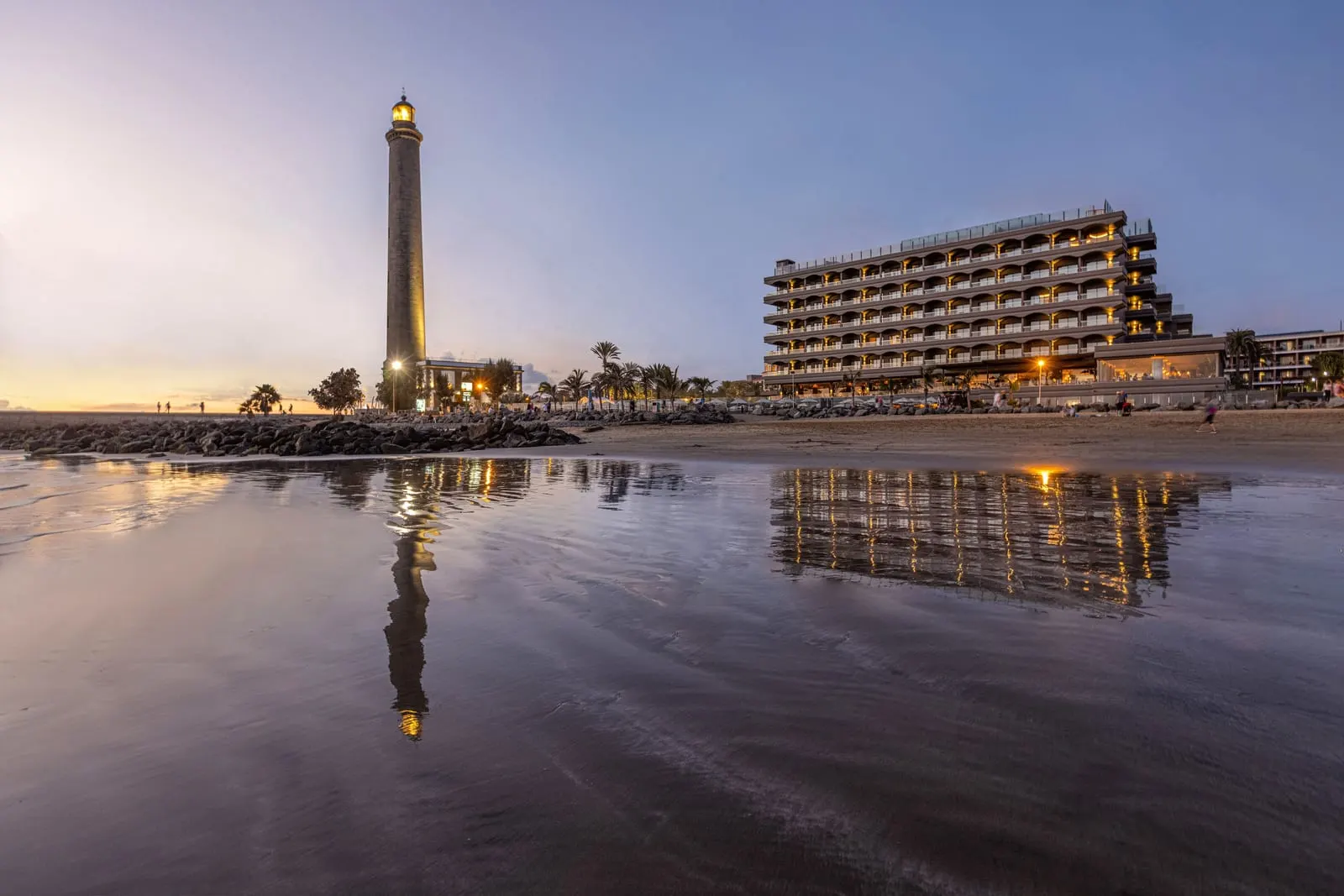 Hotel Faro, a Lopesan Collection Hotel: The hotel and the lighthouse from the beach at dusk