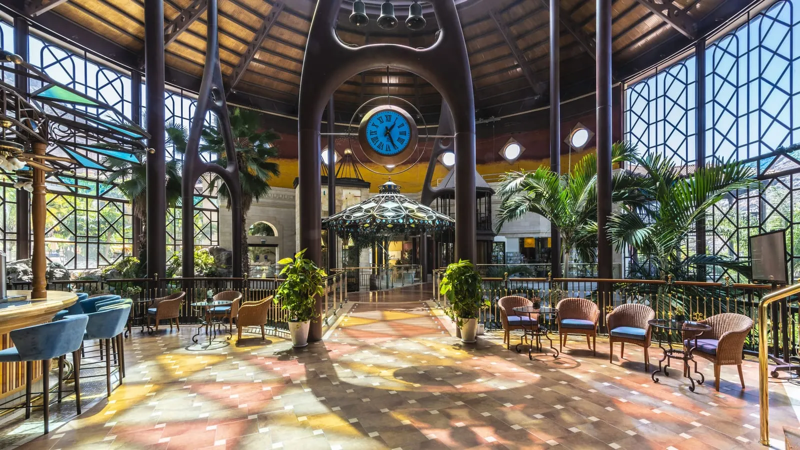 Hotel Cordial Mogán Playa: Palms and a clock in the glass-walled lobby