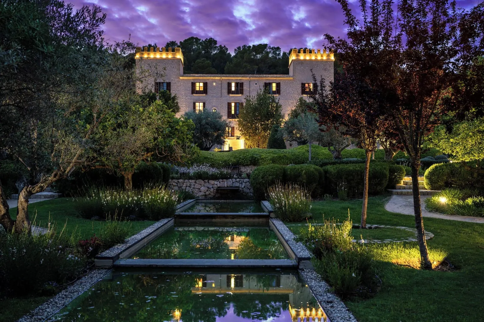 Castell Son Claret: The crenellated 1888 front at dusk, above the gardens