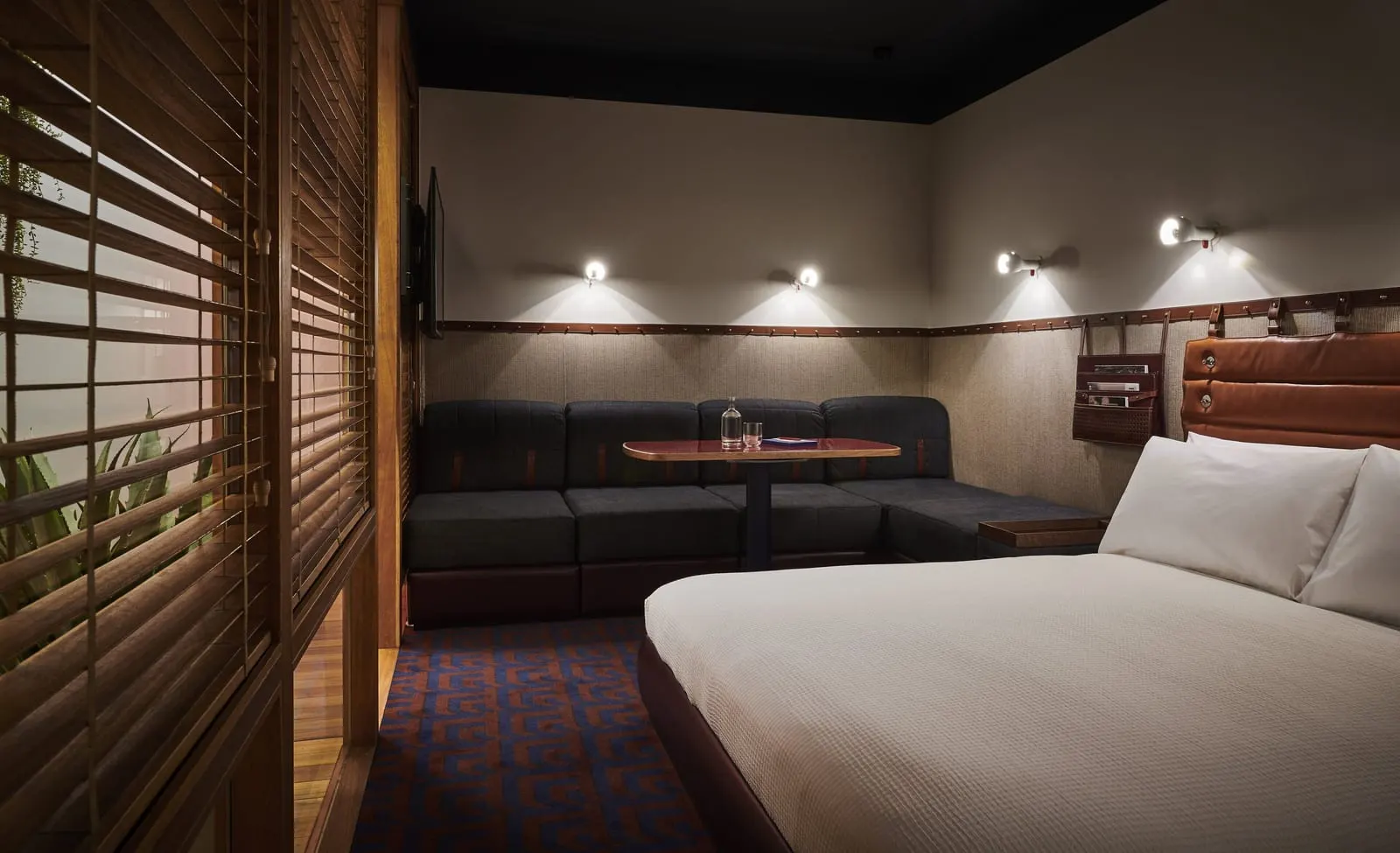 Standard King Interior at The Standard, London: the bed, a dark built-in sofa, wall lights and wooden slatted screens