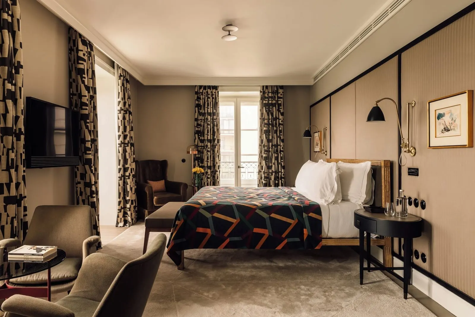 Bairro Alto Signature Suite at Bairro Alto Hotel: the bed with a geometric throw, two armchairs, a TV and a French window