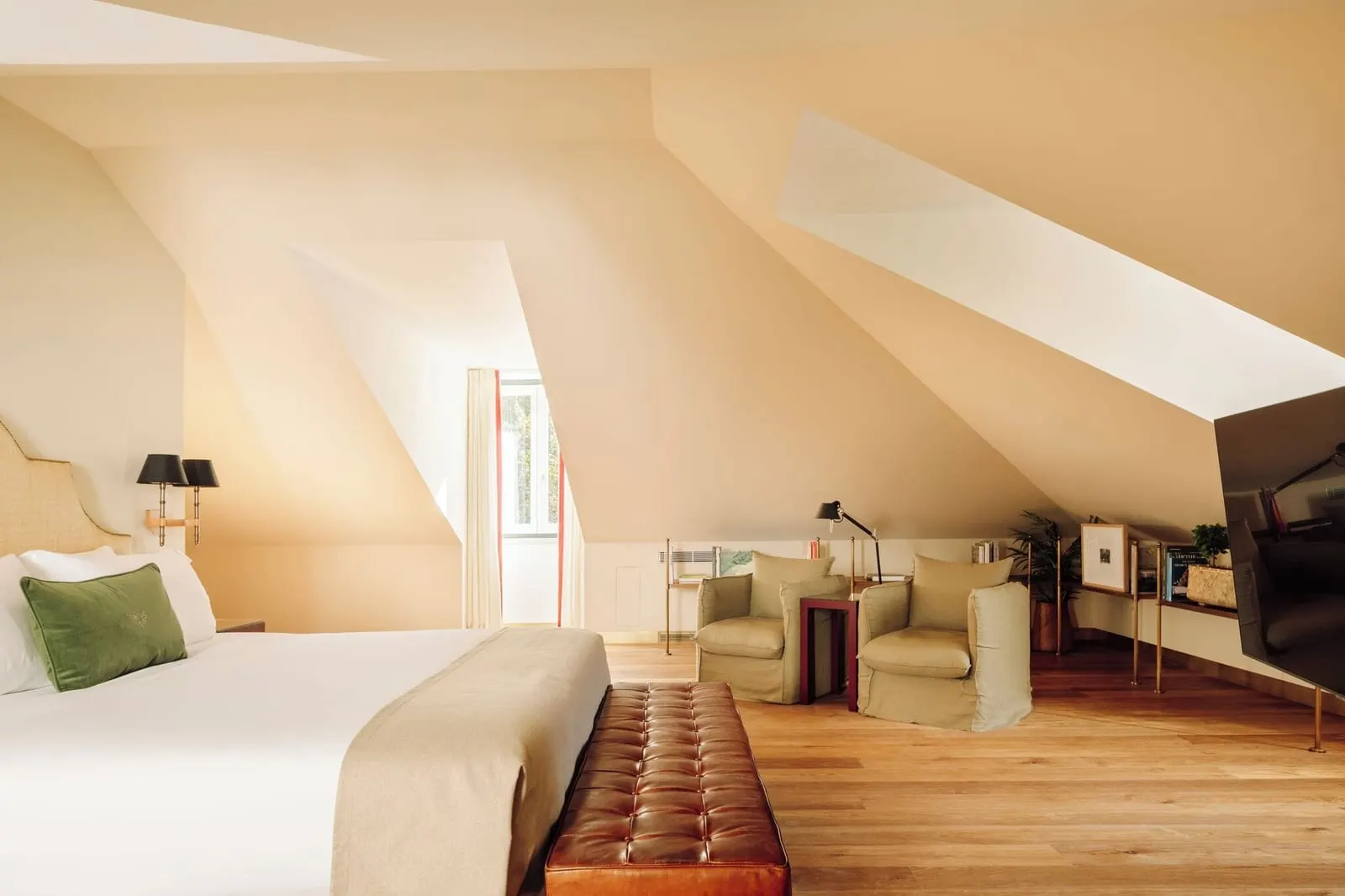 Attic Suite at Hotel das Amoreiras: the bed, a leather bench and two armchairs under the sloping mansard ceiling