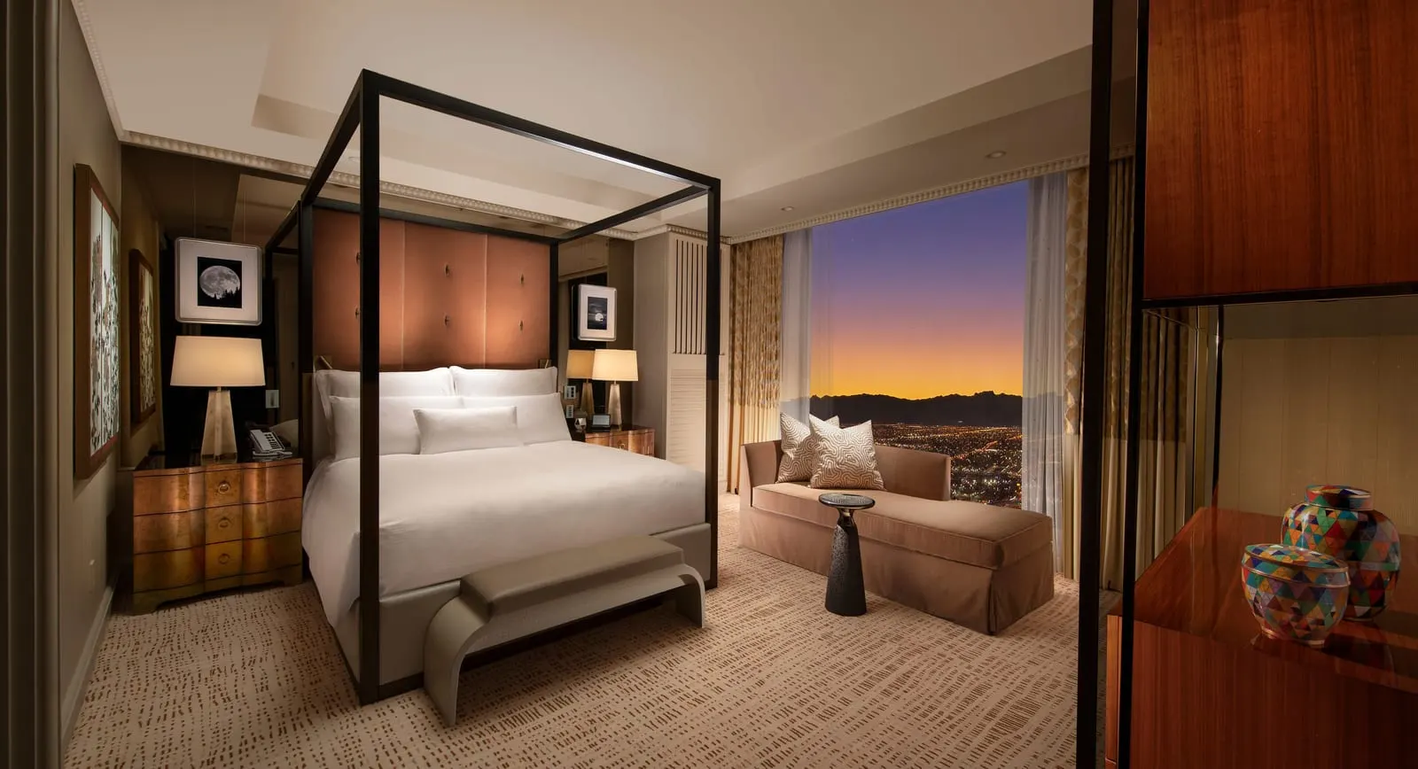 Wynn Tower Suite Parlor at Wynn Las Vegas: the bedroom, with a king bed under a canopy frame, a tall padded headboard, a bench at the foot of the bed and a chaise longue by the window