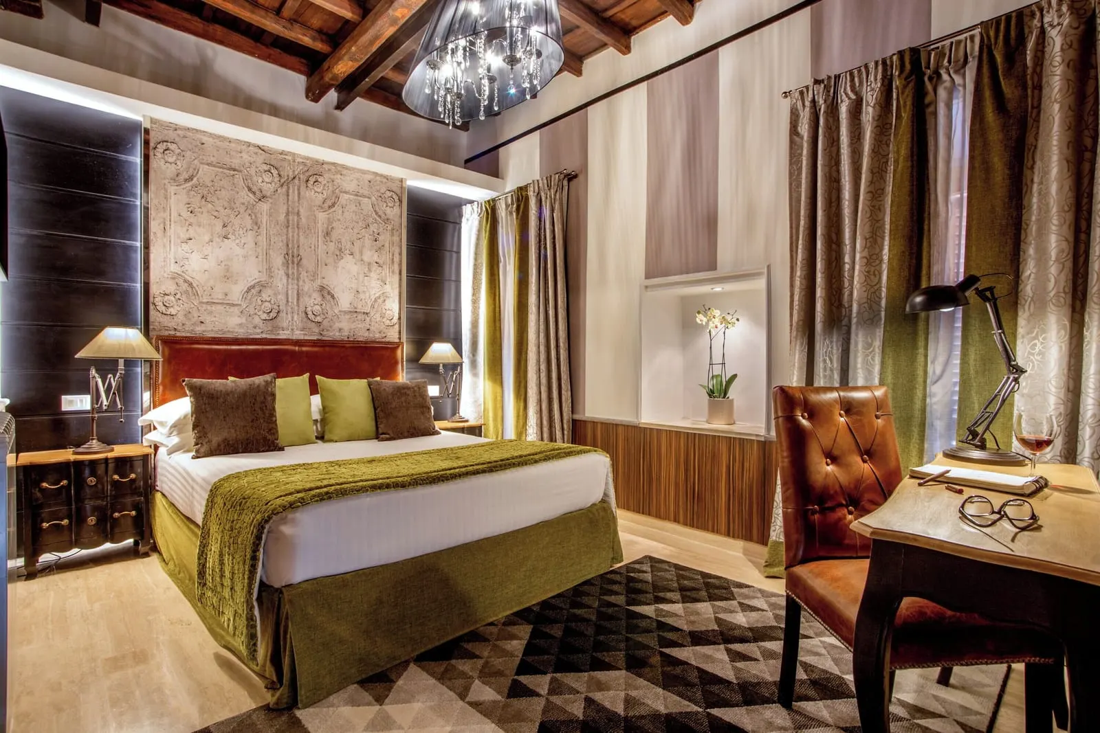 Town House Apartment at The Inn at the Roman Forum: a bed with a green throw under a carved panel, and a desk by the window