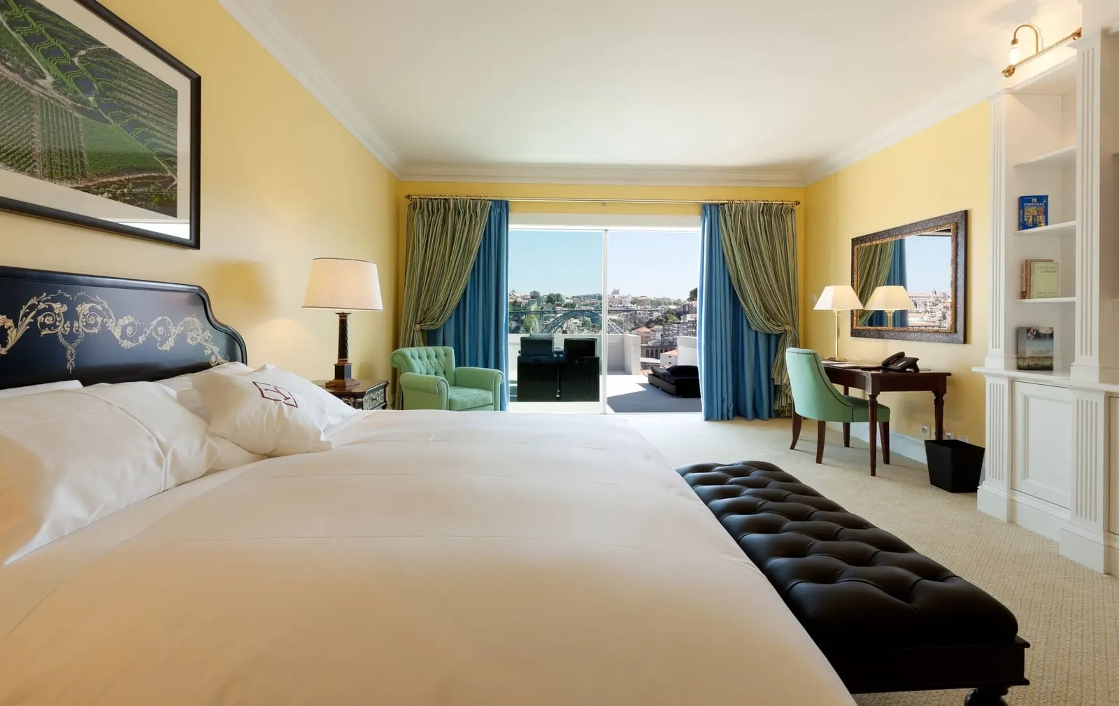 Superior Deluxe Panoramic Room at The Yeatman: the bed, a desk and shelves, with the terrace and city rooftops through the window