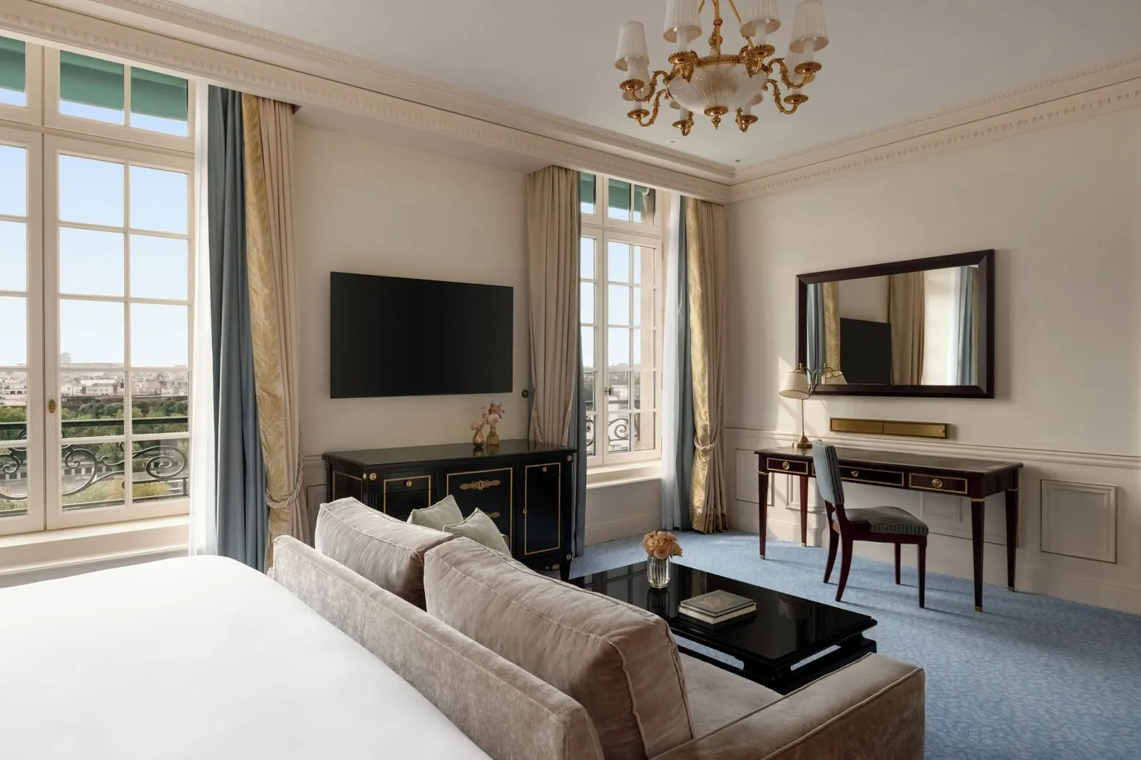 Eiffel View Room at Shangri-La Paris: the sitting area, with a sofa at the foot of the bed, a writing desk, a gilt chandelier and two sets of tall French windows