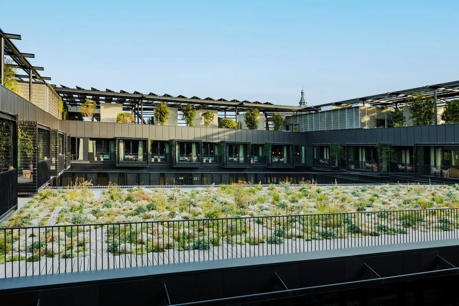 Deluxe Balcony at Hôtel Madame Rêve: the planted hanging garden in the middle of the block, ringed by the glazed fronts and railings of the garden-side rooms, with the slatted roof canopy above