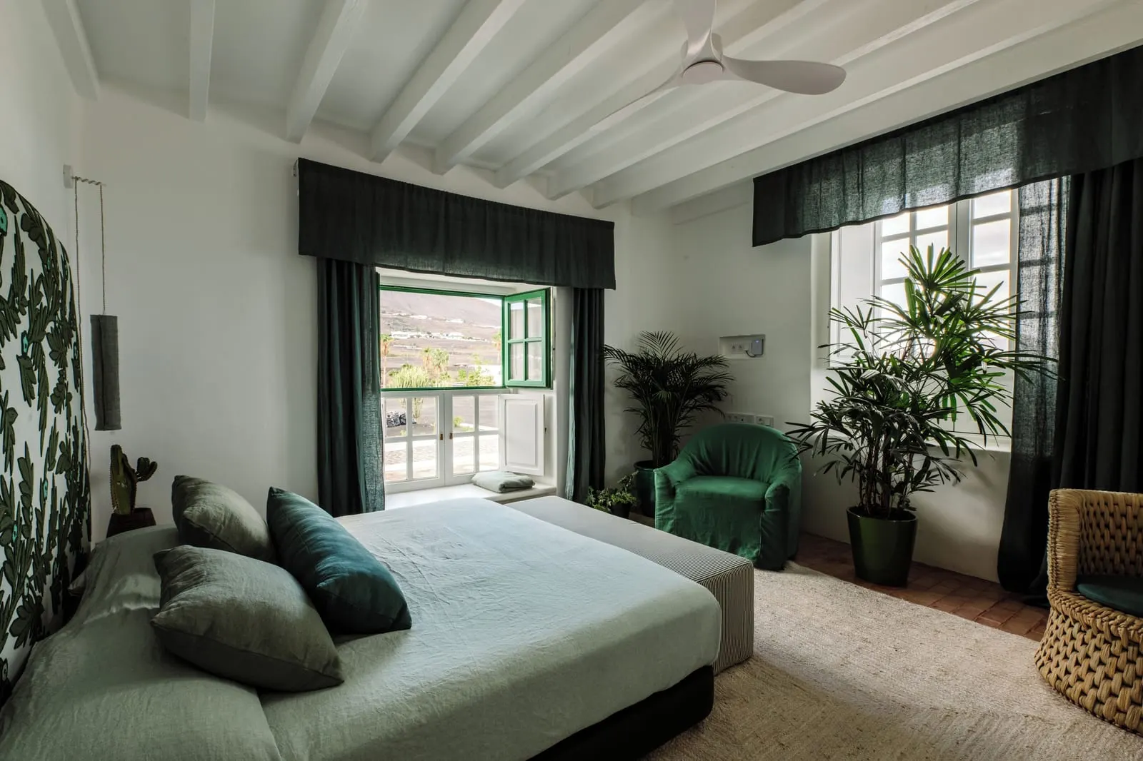 Superior Room à l'Hotel César Lanzarote : un lit avec un fauteuil vert et des plantes dans une chambre blanche à poutres, avec une grande fenêtre