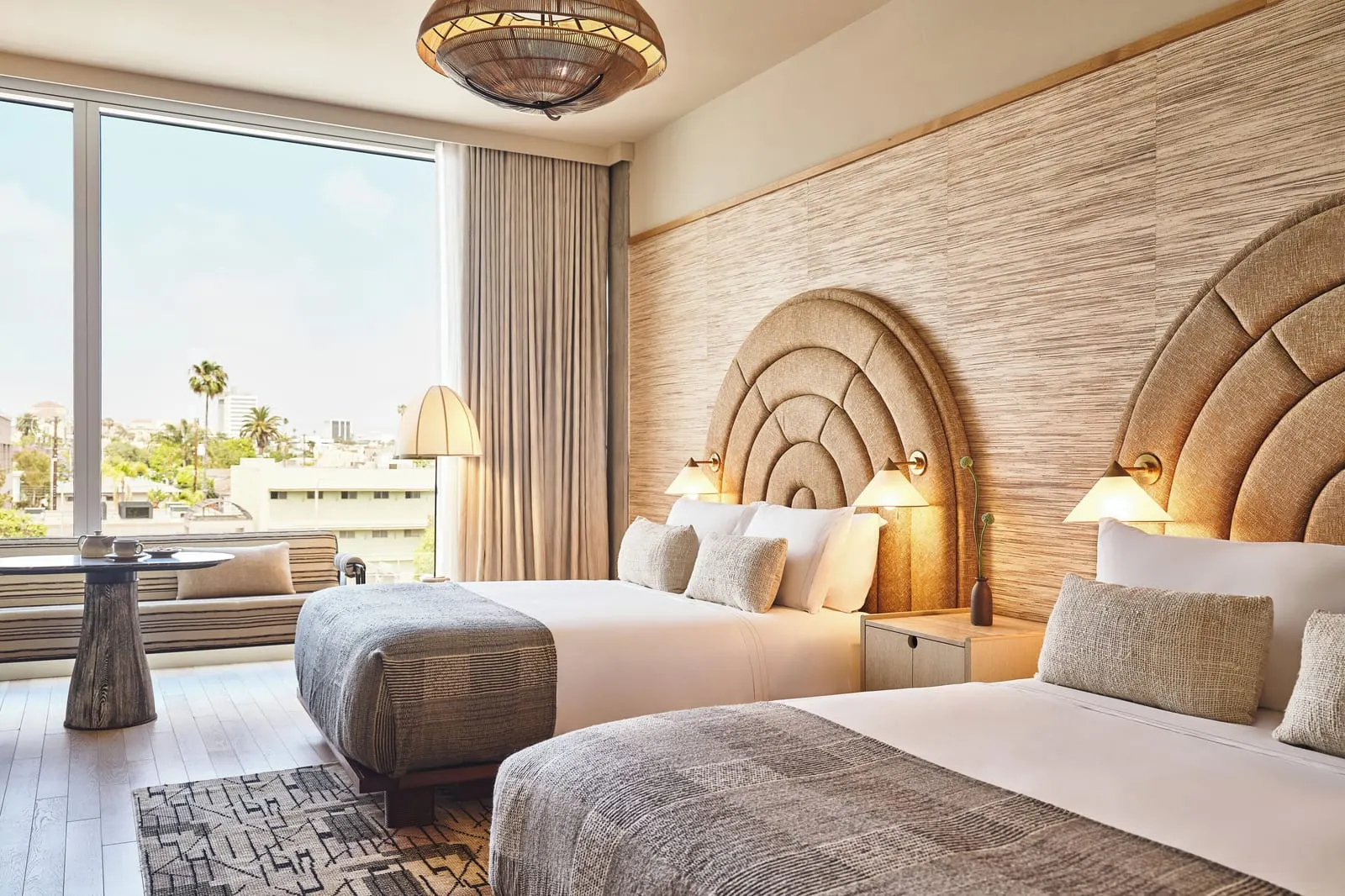 Premier Double Queen im Santa Monica Proper Hotel: zwei Queensize-Betten mit bogenförmigen Kopfteilen, neben einem Fenstersitz und einem kleinen runden Tisch