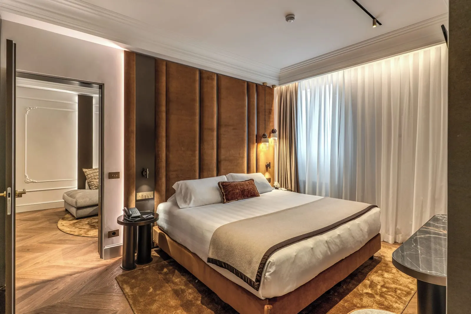 Romantic Suite at Eitch Borromini Palazzo Pamphilj: a double bed against a tall padded headboard, with a sitting room through the door