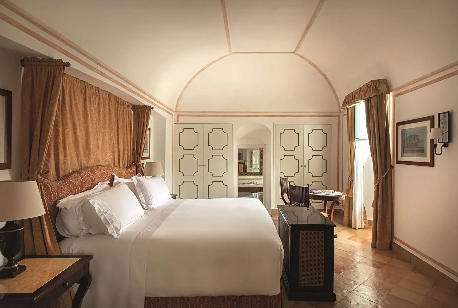 Superior Suite at Caruso, A Belmond Hotel: a bed with a draped canopy under a vaulted ceiling, with painted wardrobe doors and a small writing table