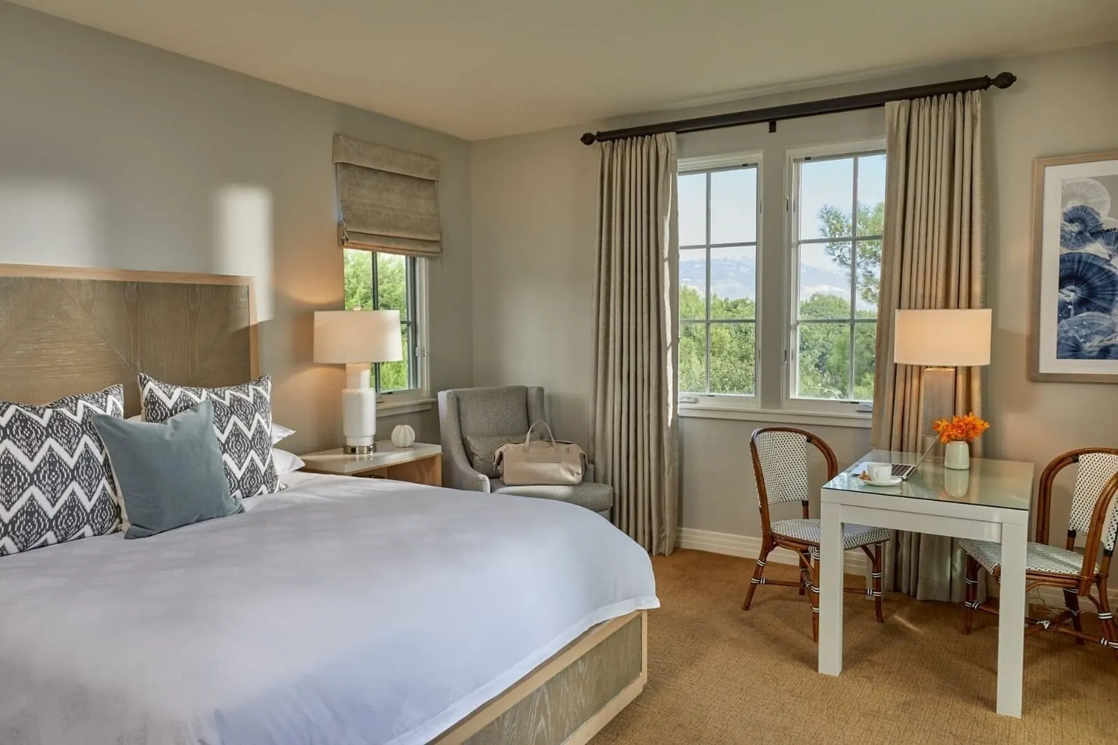 Three-Bedroom Casita at Terranea Resort: a bedroom with a bed, a white writing table with two cane chairs and tall curtained windows