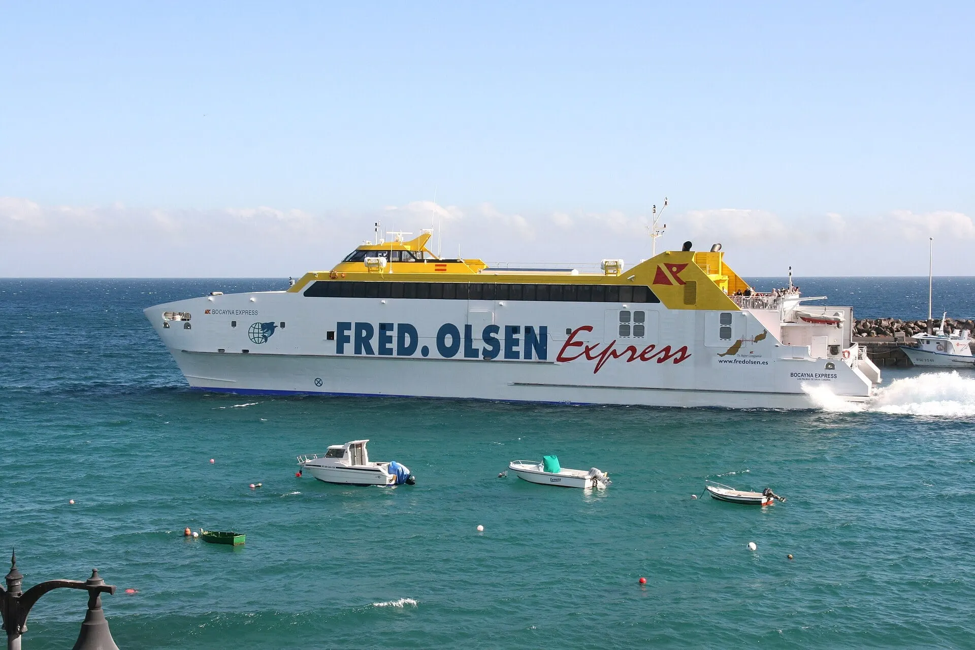 The Fred. Olsen fast ferry Bocayna Express at speed off the breakwater at Playa Blanca on a turquoise sea