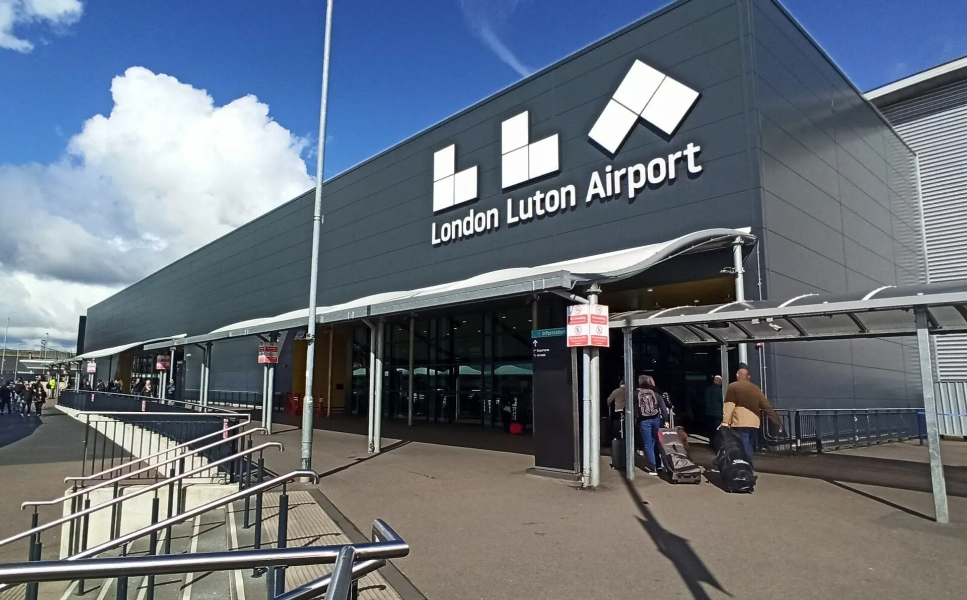 The entrance to the London Luton Airport terminal under a blue sky