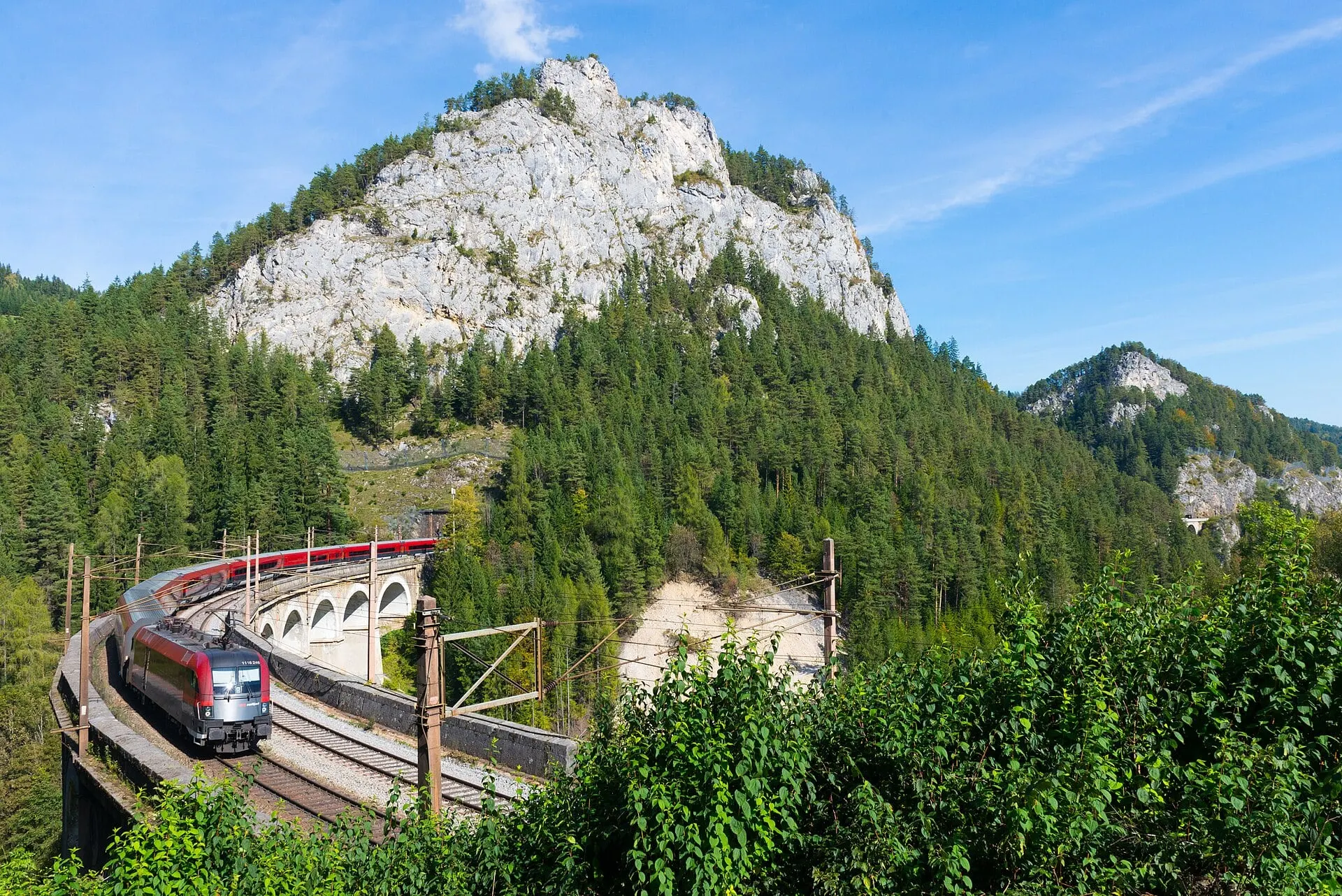 An ÖBB Railjet curving across the Kalte Rinne viaduct below the limestone Polleroswand on the Semmering Railway