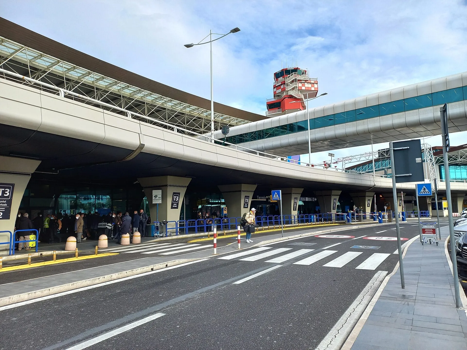 The Terminal 3 departures forecourt at Rome Fiumicino, with the red and white control tower behind