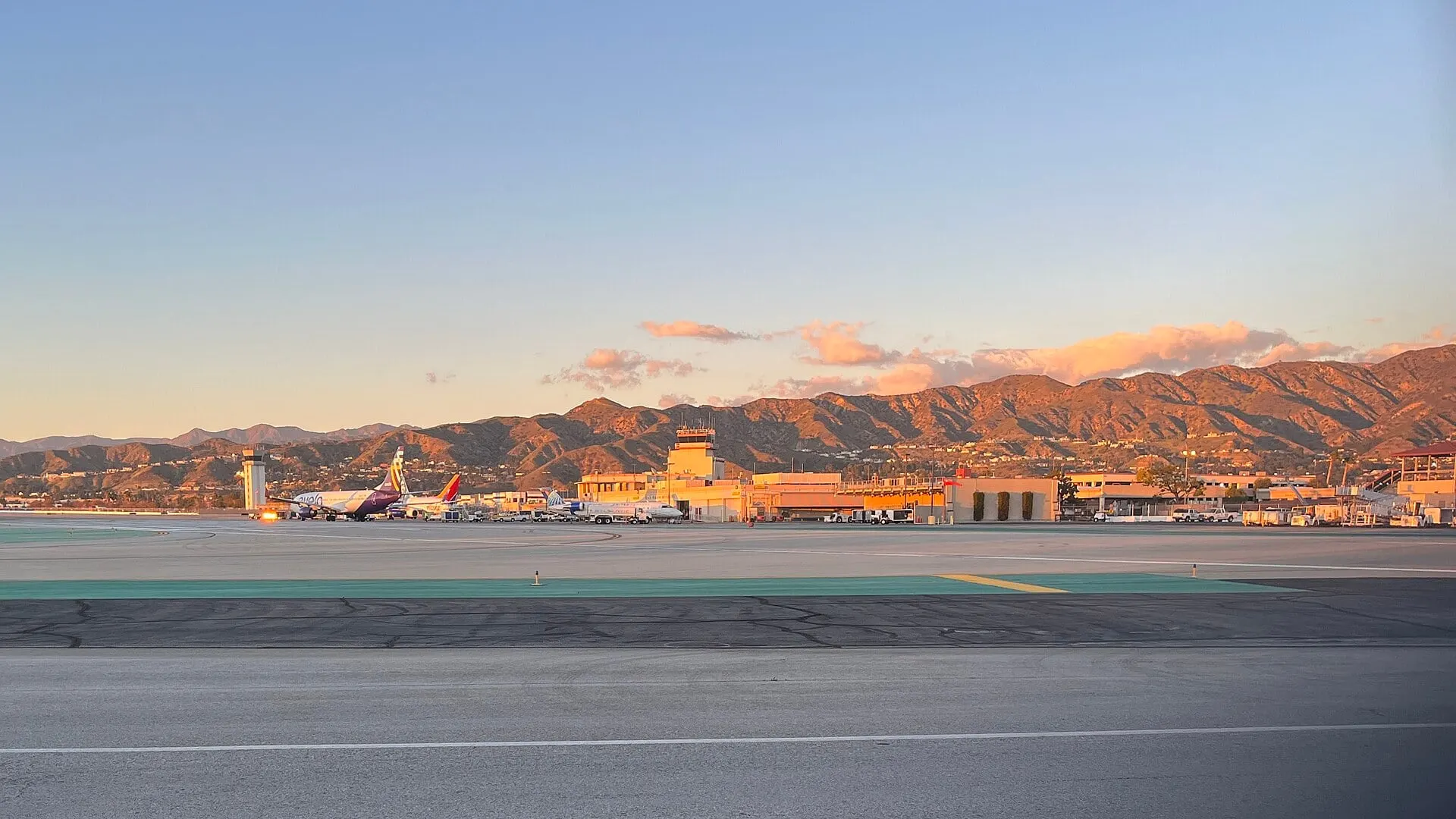 The runway at Hollywood Burbank Airport at sunset, with the Verdugo Mountains behind