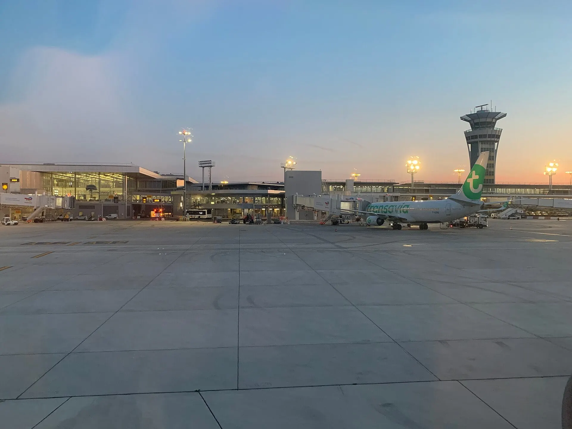 The Paris Orly terminal and control tower at dusk, with a Transavia jet at the gate
