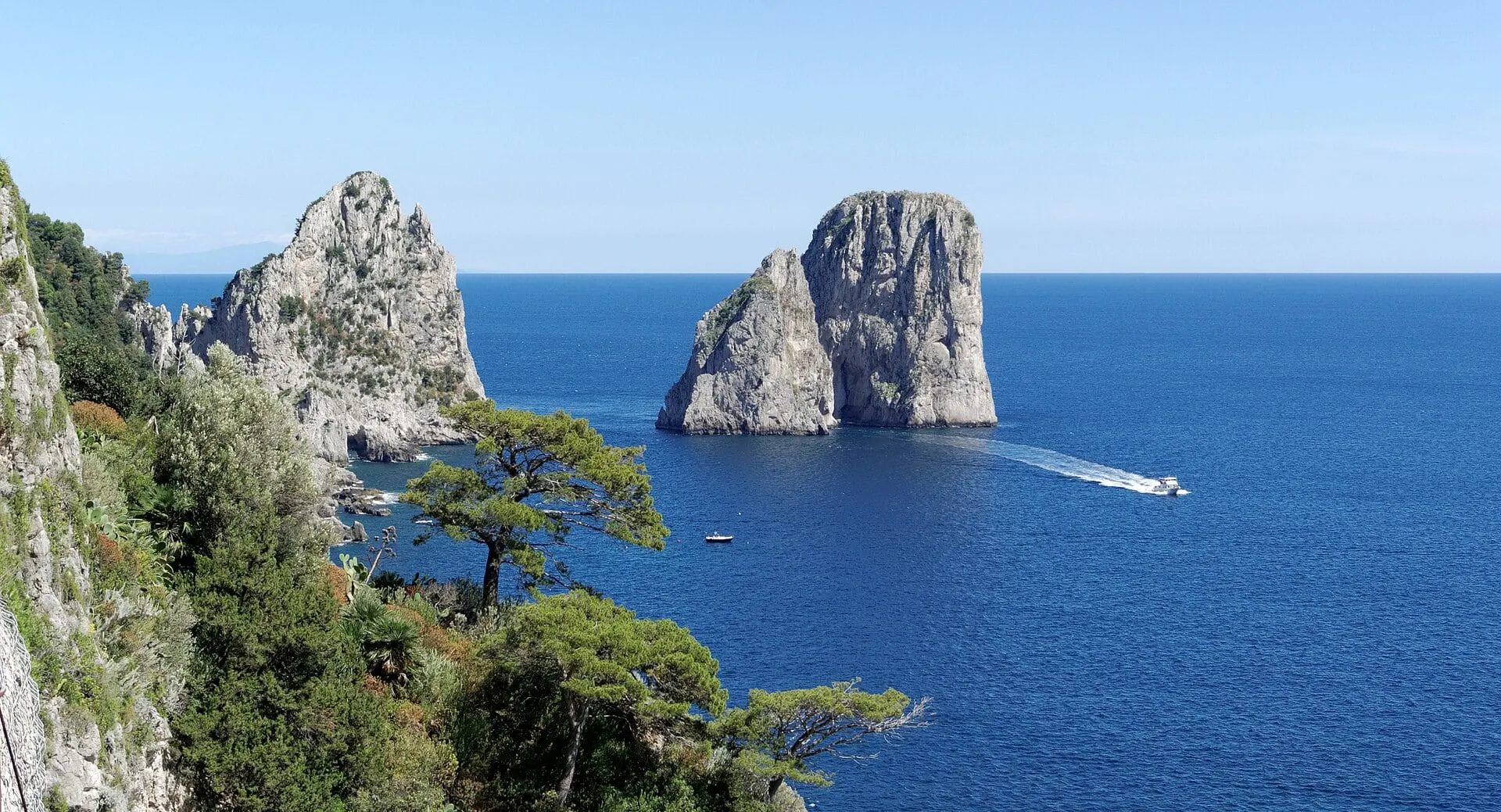 The Faraglioni rock stacks off Capri in deep blue water with a boat wake
