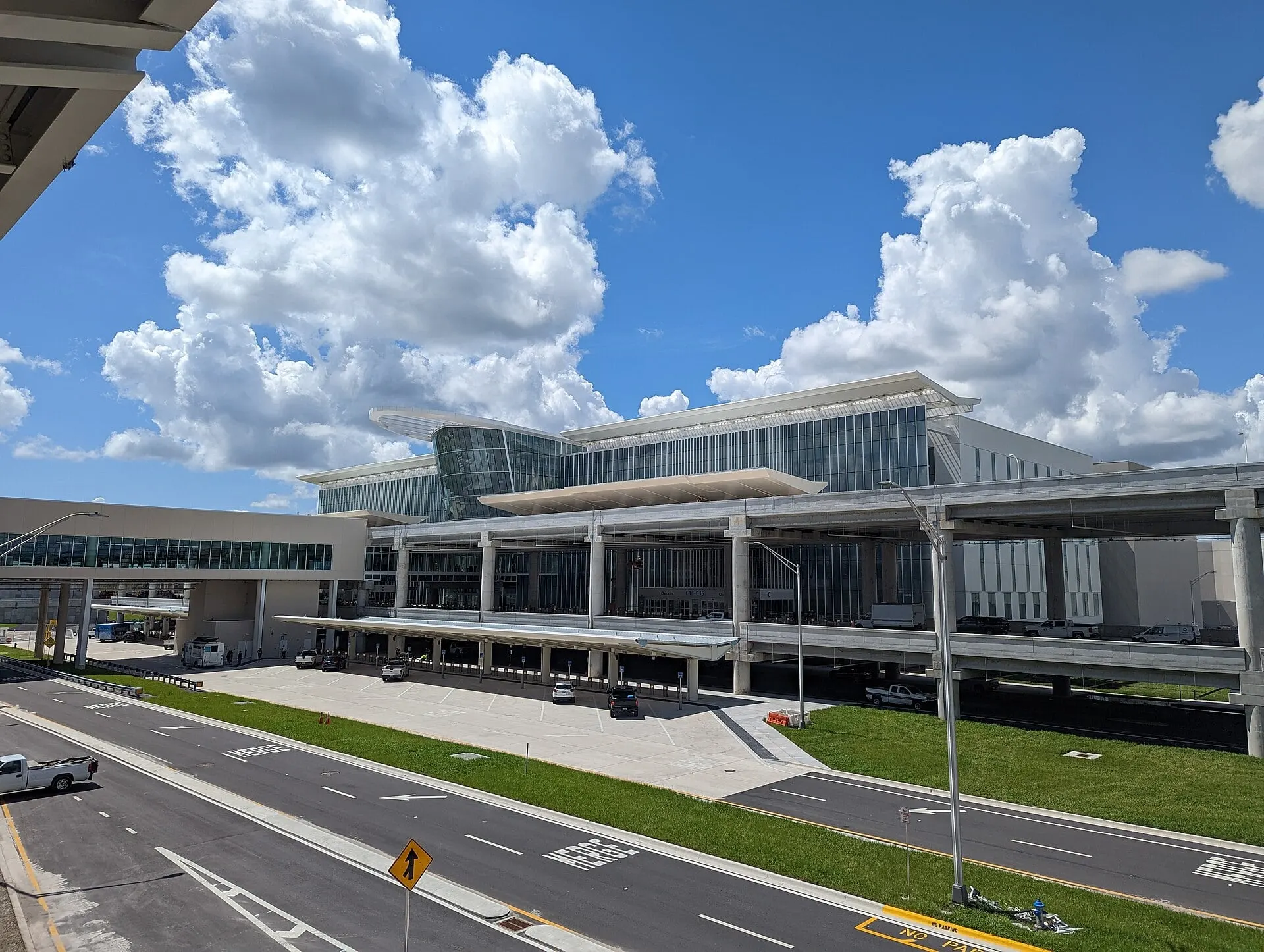 The glass front of Terminal C at Orlando International Airport under a summer sky