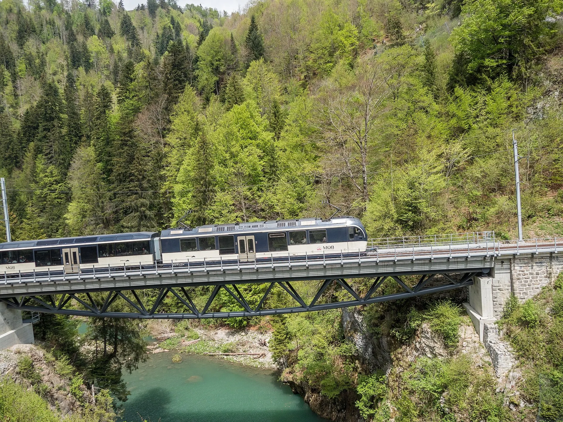An MOB train crosses the steel bridge over the turquoise Sarine river at Rossinière in the Pays-d'Enhaut.