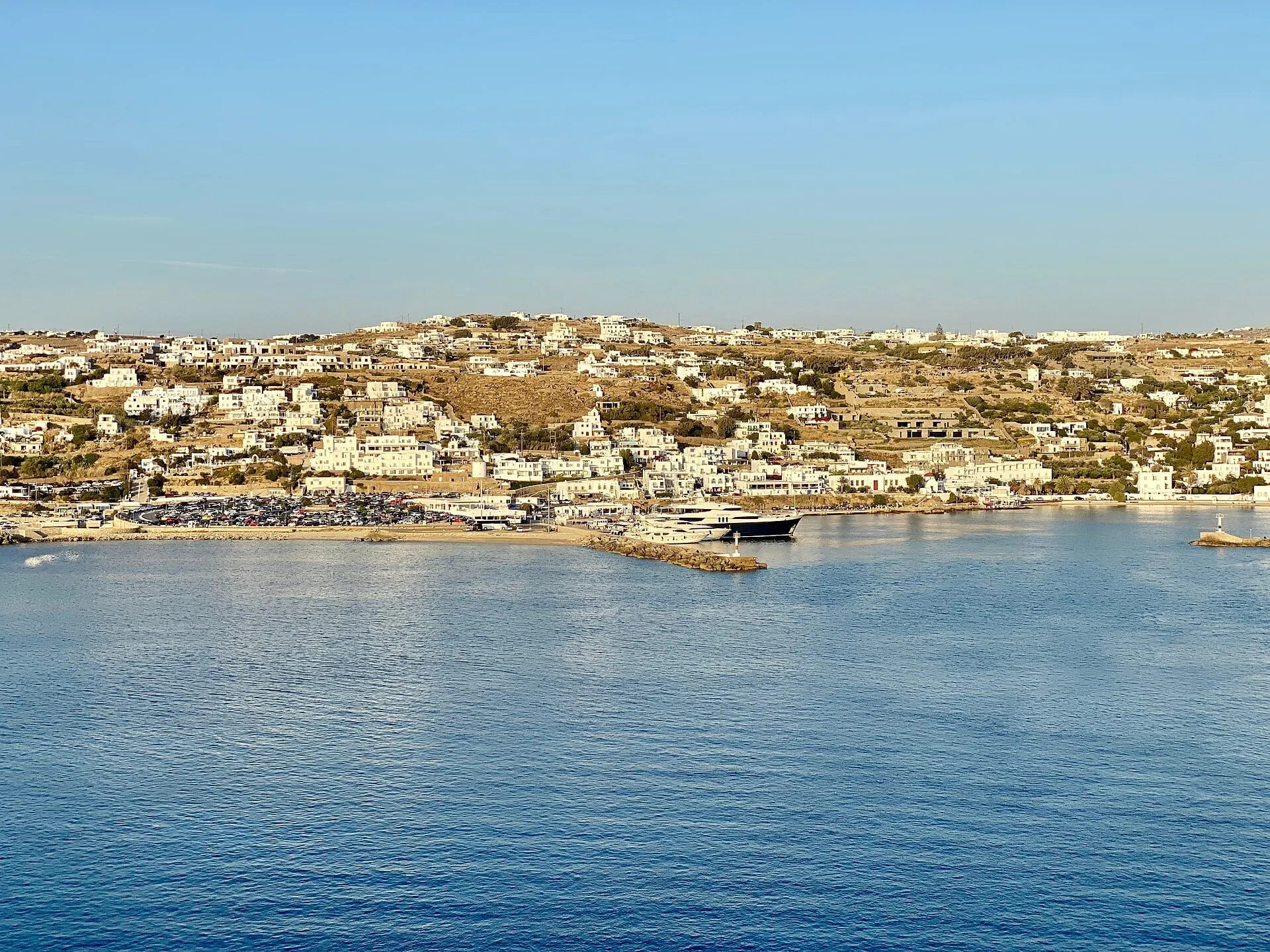 Der erste Blick auf die Stadt Mykonos vom Meer aus in tiefem goldenem Licht