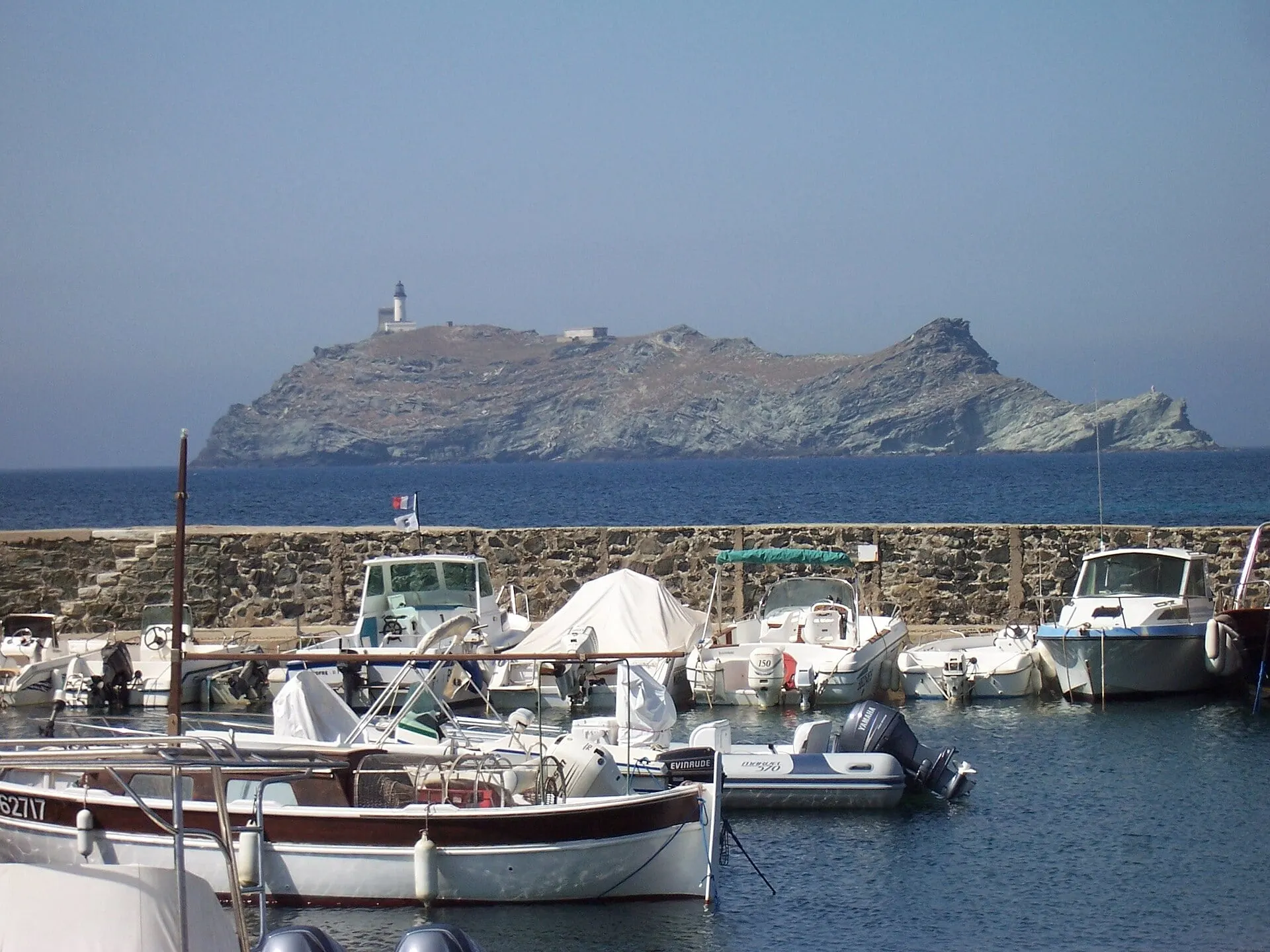The Giraglia islet and its lighthouse off the tip of Cap Corse, seen beyond the harbour wall at Barcaggio
