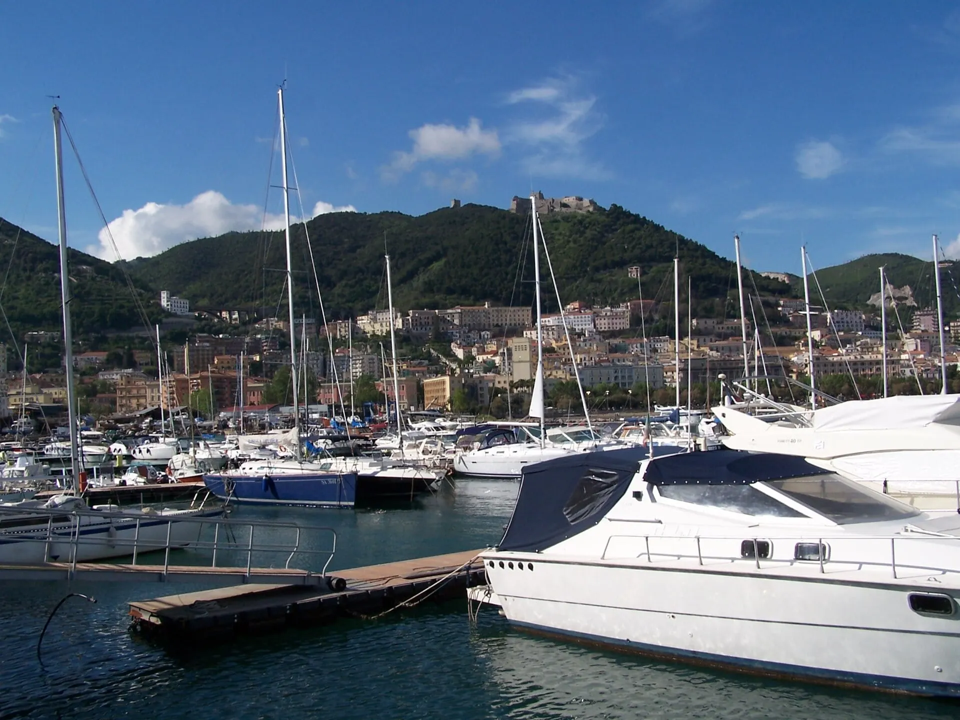 Yachts moored in the port of Salerno beneath green hills