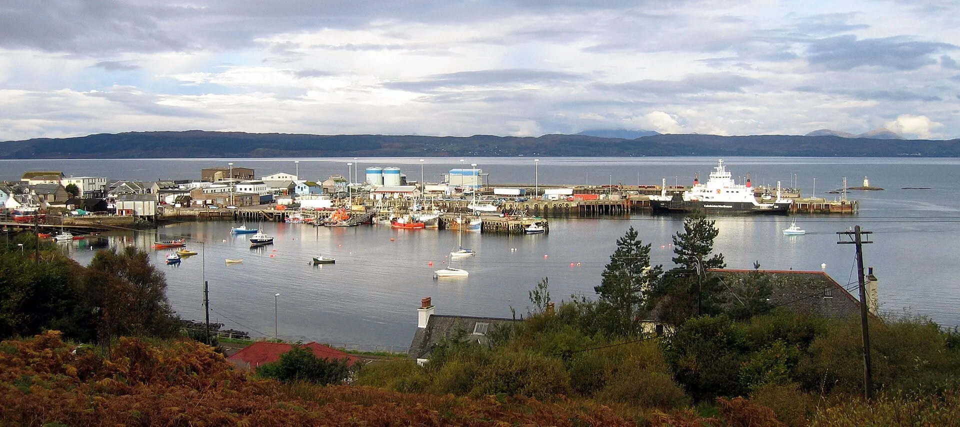 Mallaig harbour with fishing boats and a CalMac ferry at the pier, and the hills of Skye across the sound.