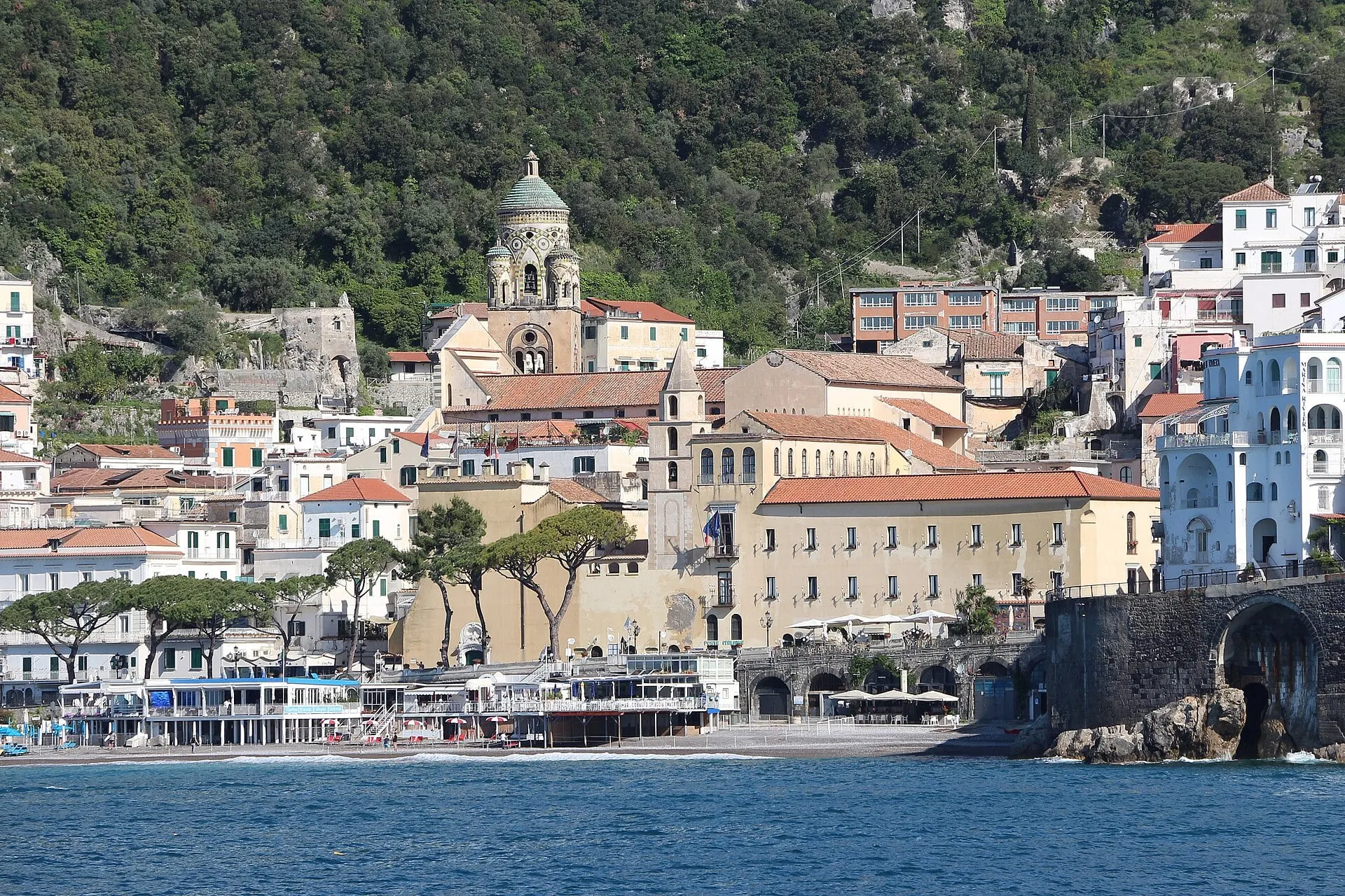 Amalfi seen from the water, its cathedral bell tower rising above the beach front