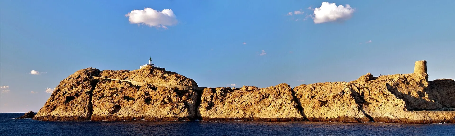 The red rocks of the Île de la Pietra at L'Île-Rousse in golden light, with its lighthouse and Genoese tower