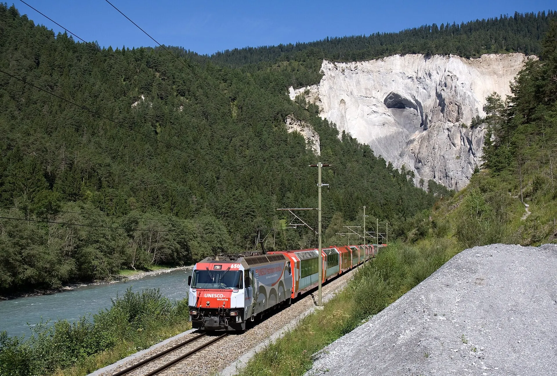 The Glacier Express running beside the Rhine below the pale cliffs of the Rhine Gorge