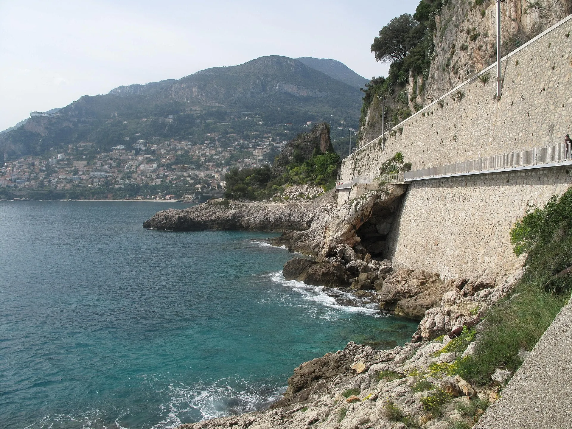 The rocky shore of Cap Martin beneath the stone wall that carries the railway at Roquebrune-Cap-Martin.