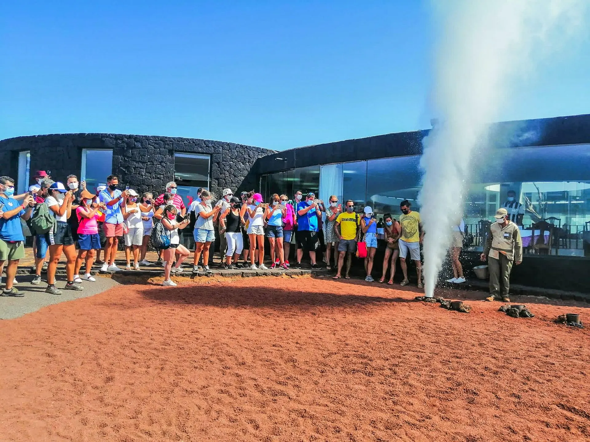 A park worker pours water into a hole on the Islote de Hilario and a column of steam erupts as visitors watch