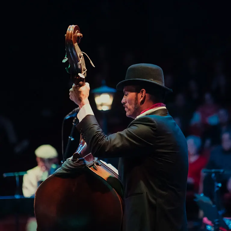 The Jazz Roomで、山高帽をかぶったコントラバス奏者が観客を背に演奏している