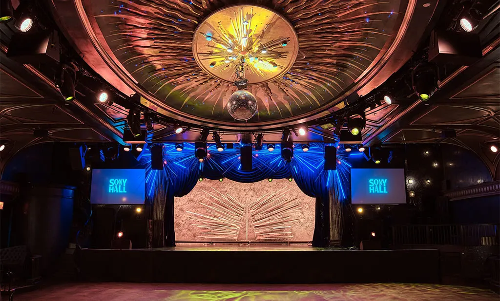 The empty stage at Sony Hall, under a domed gilded ceiling with a mirror ball and blue stage lights