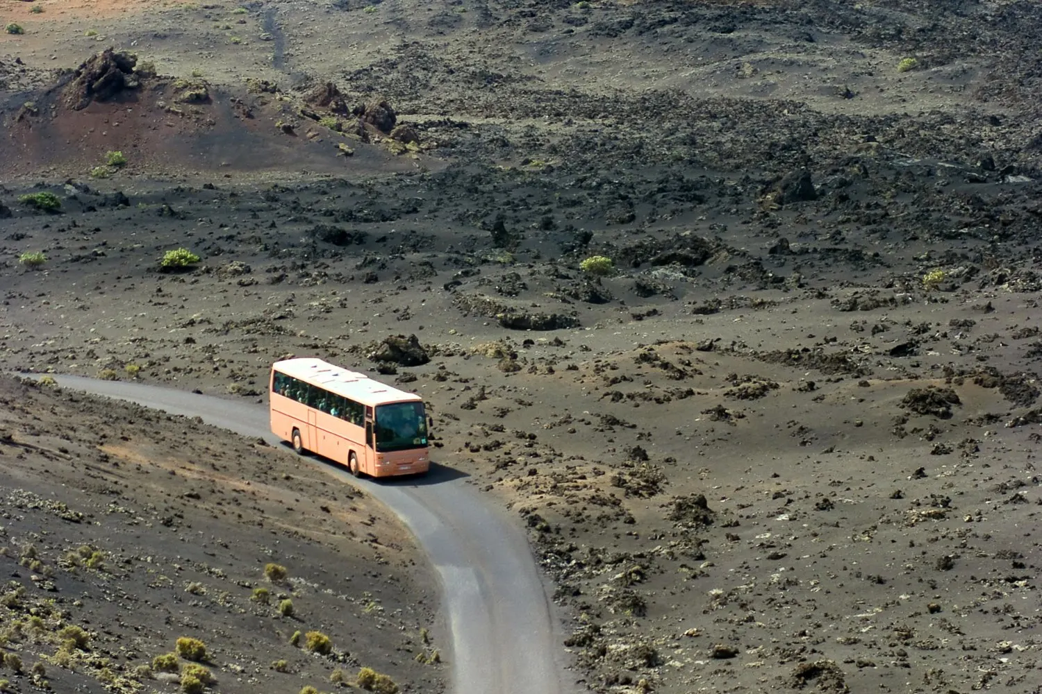 A coach on a narrow road through the black lava fields of Timanfaya