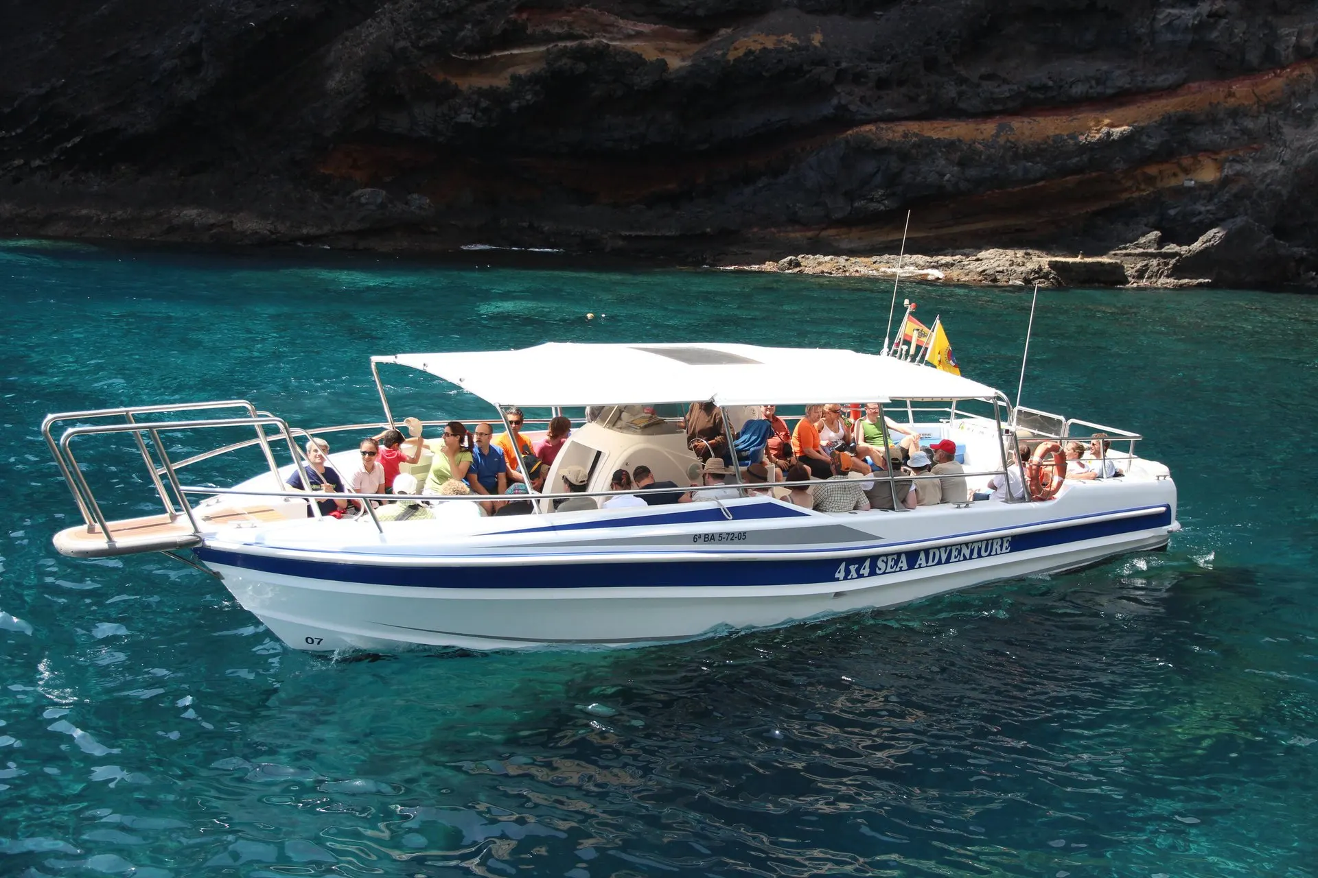 The boat moored in clear turquoise water under the cliffs for the swim stop