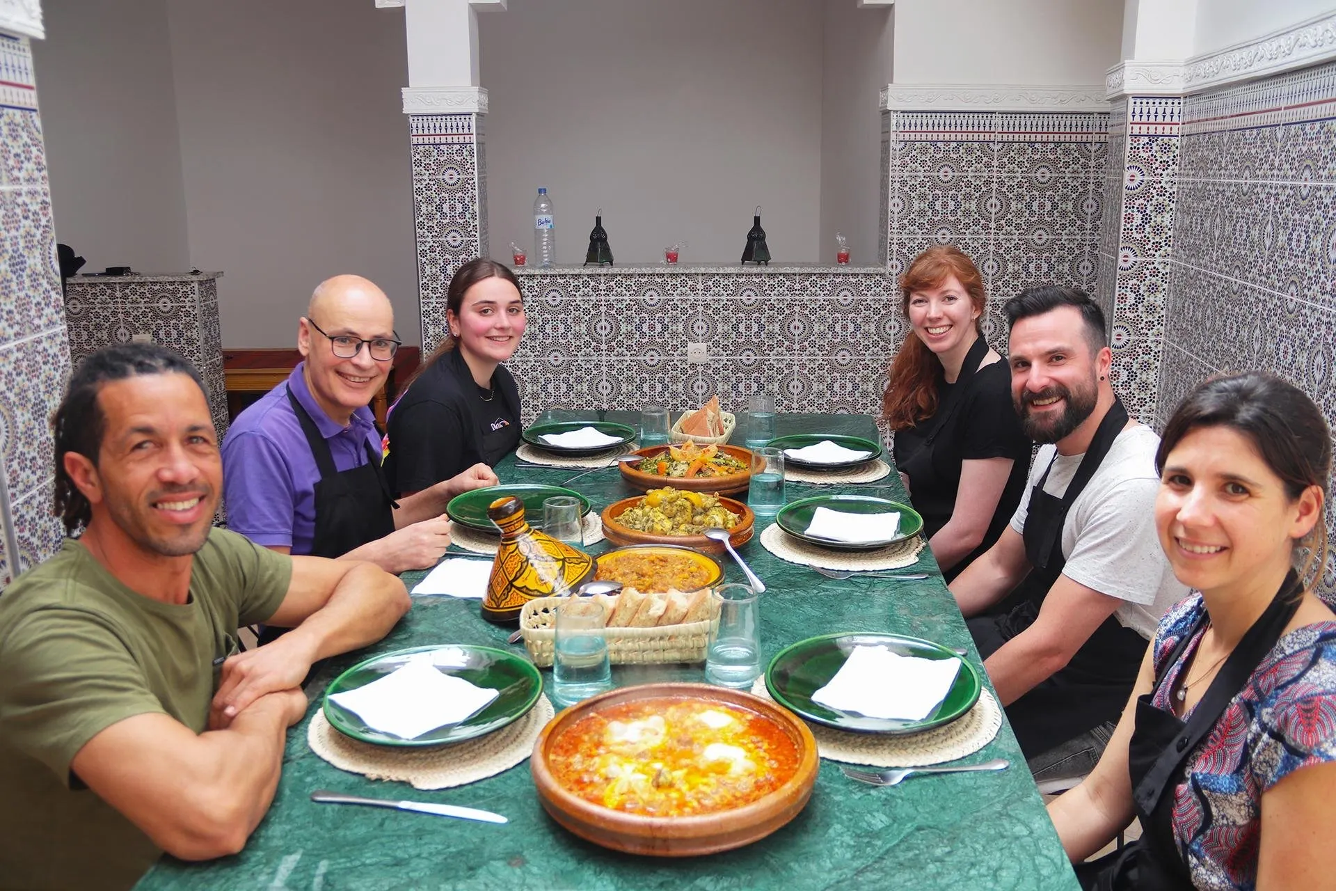 Guests at the table with the dishes they cooked, a buffet of tagines, salads and bread