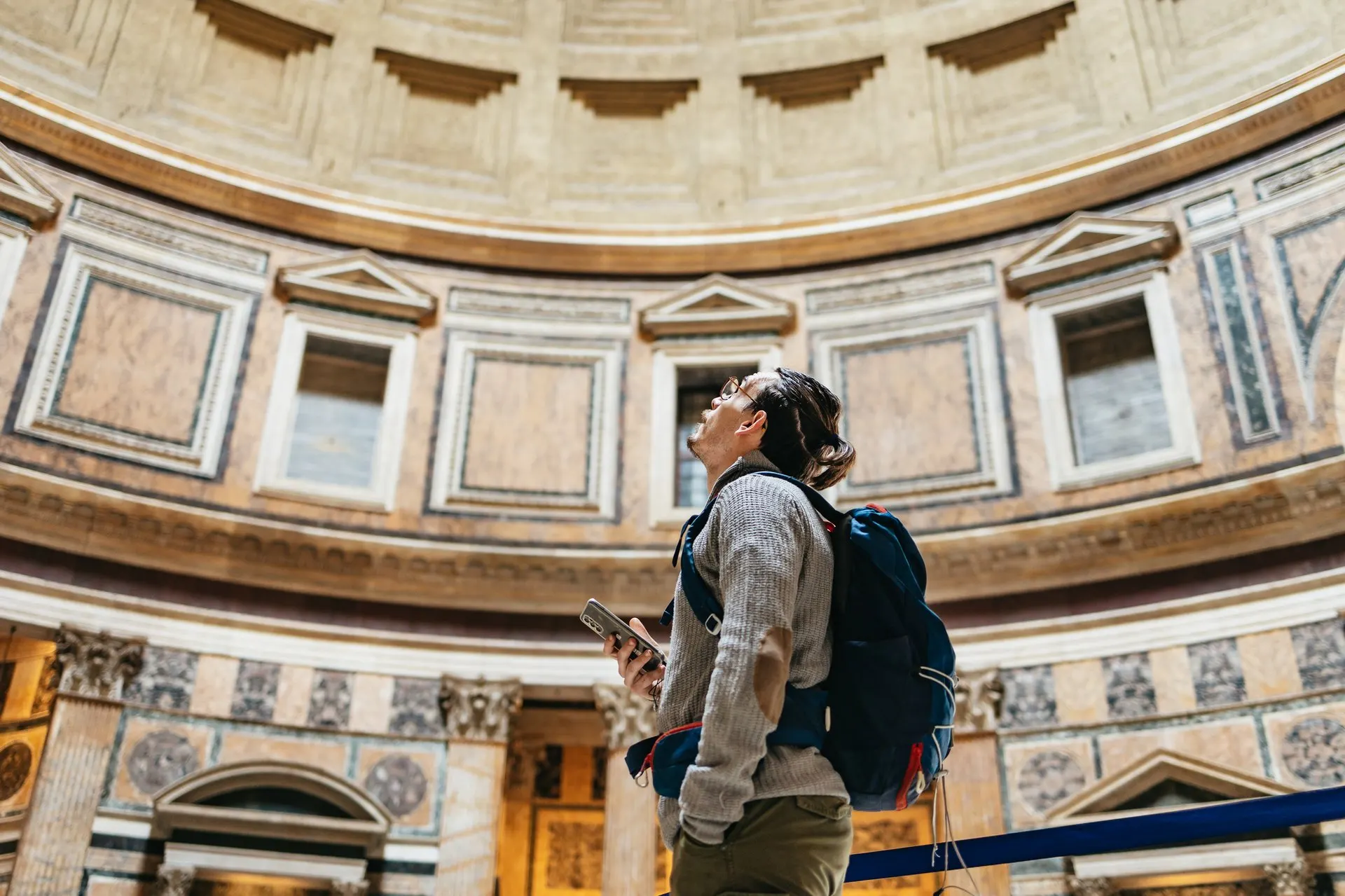 A visitor with an audio guide looking up inside the Pantheon