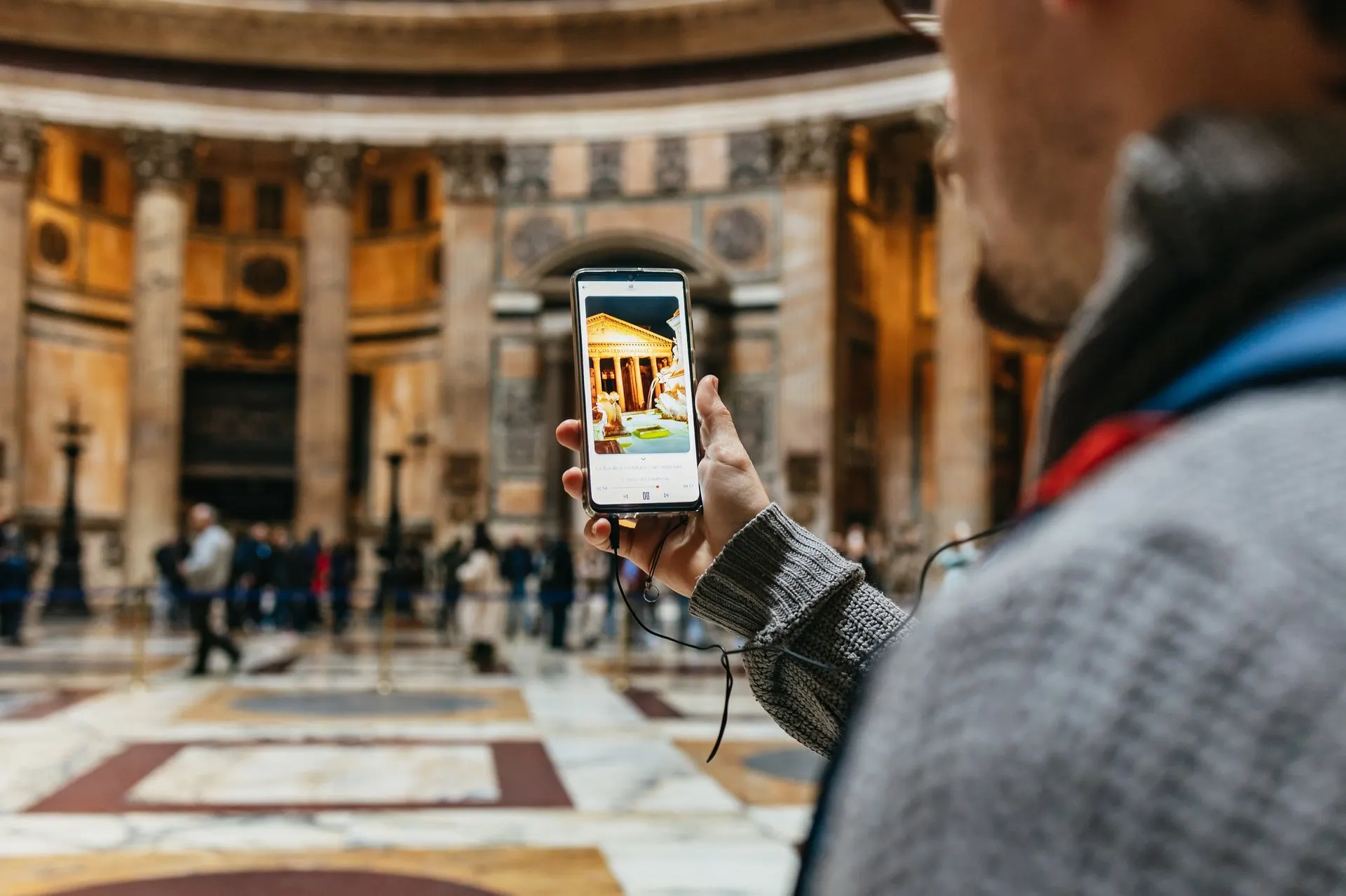 A visitor holding up a phone with the audio guide inside the Pantheon
