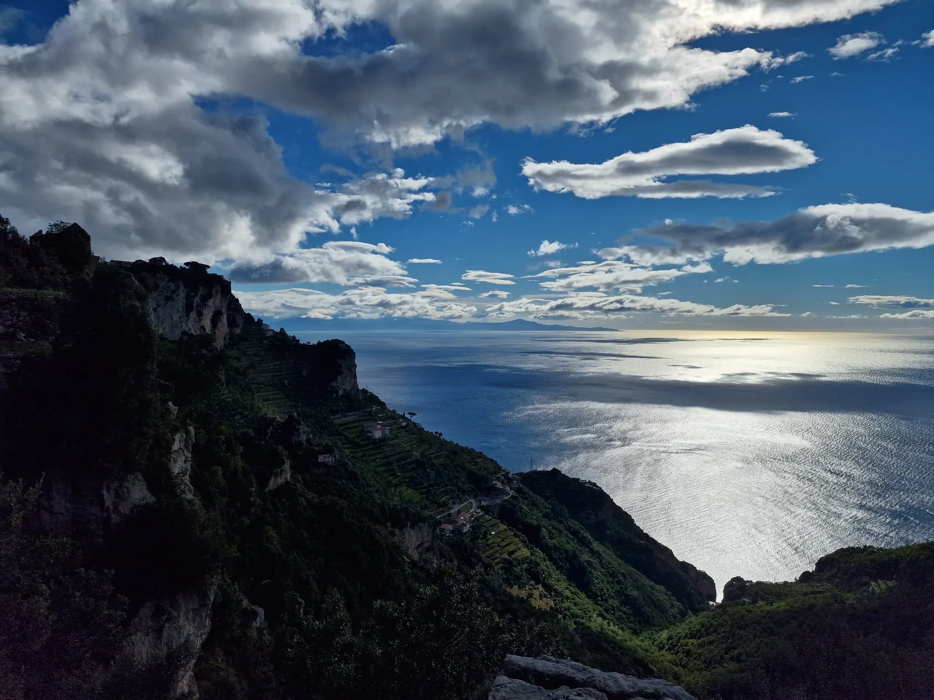 Terraced slopes falling to the sea below the Path of the Gods, with a far coastline on the horizon