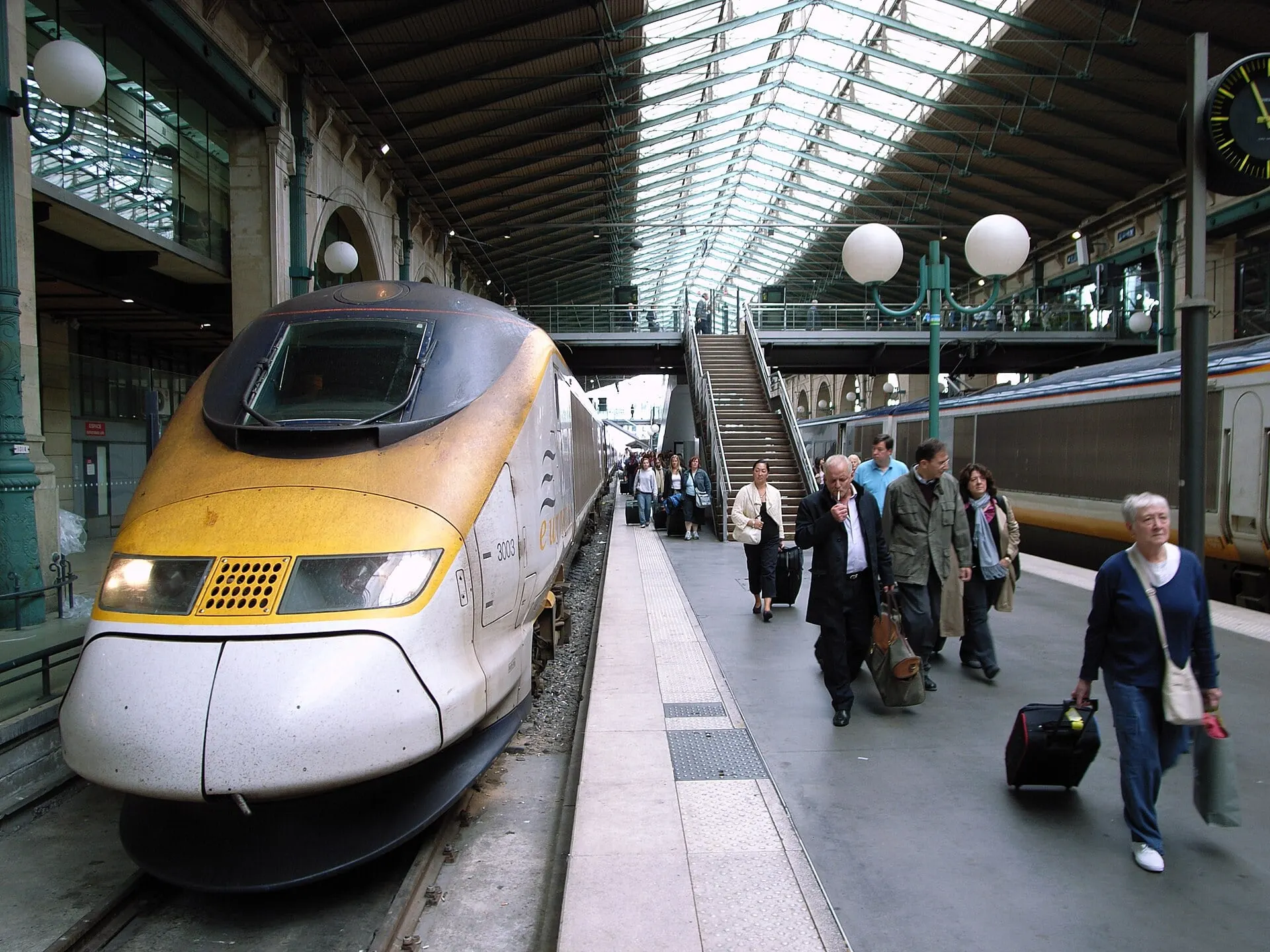 Passengers with suitcases walking off a Eurostar train on the platform at Paris Gare du Nord