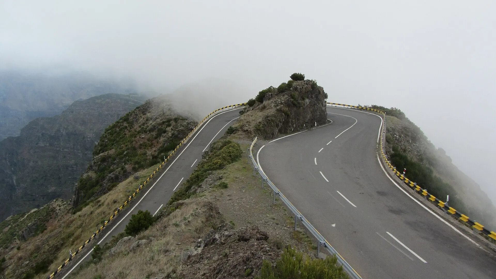 マデイラ島中央部のエンクメアダにある、雲を眼下に尾根沿いを急カーブで進む山道