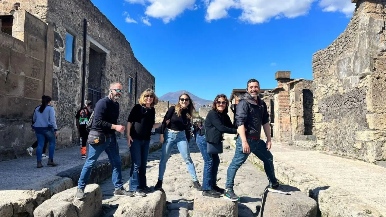 A group on a Roman street in Pompeii with Vesuvius behind