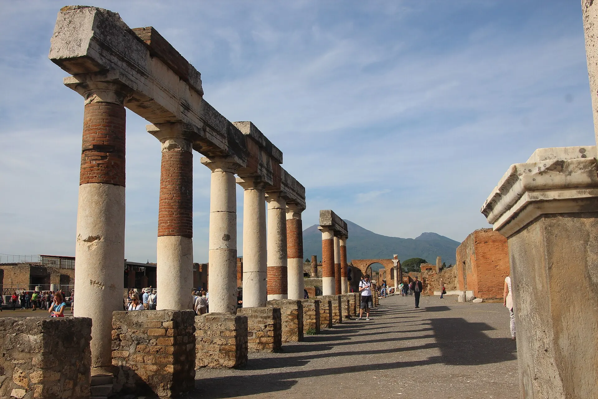 The brick and stone colonnade of the Forum at Pompeii, with Vesuvius in the distance