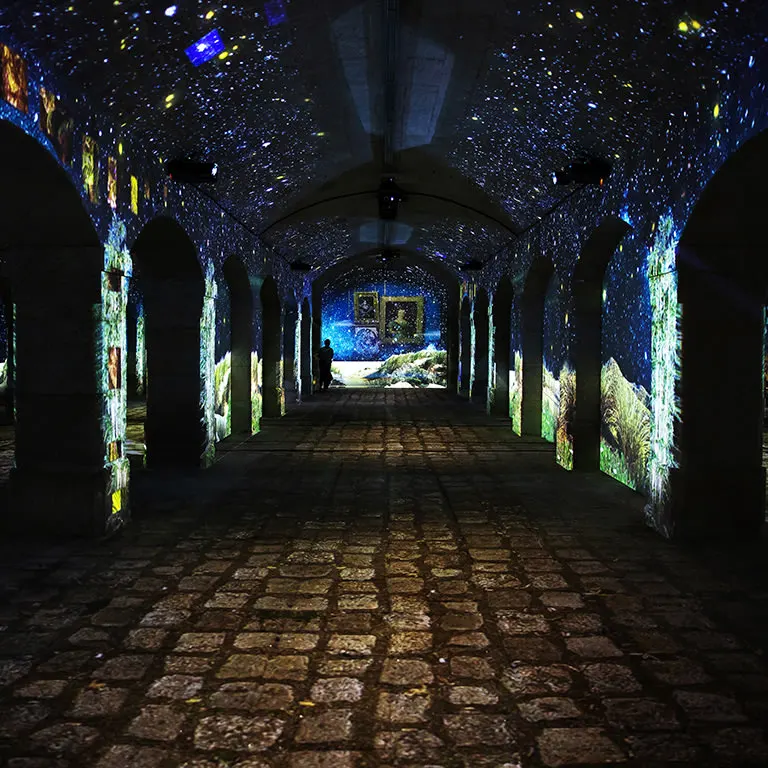 A long vaulted gallery beneath the Porto Customs House, its arches lit by projections of a starry sky