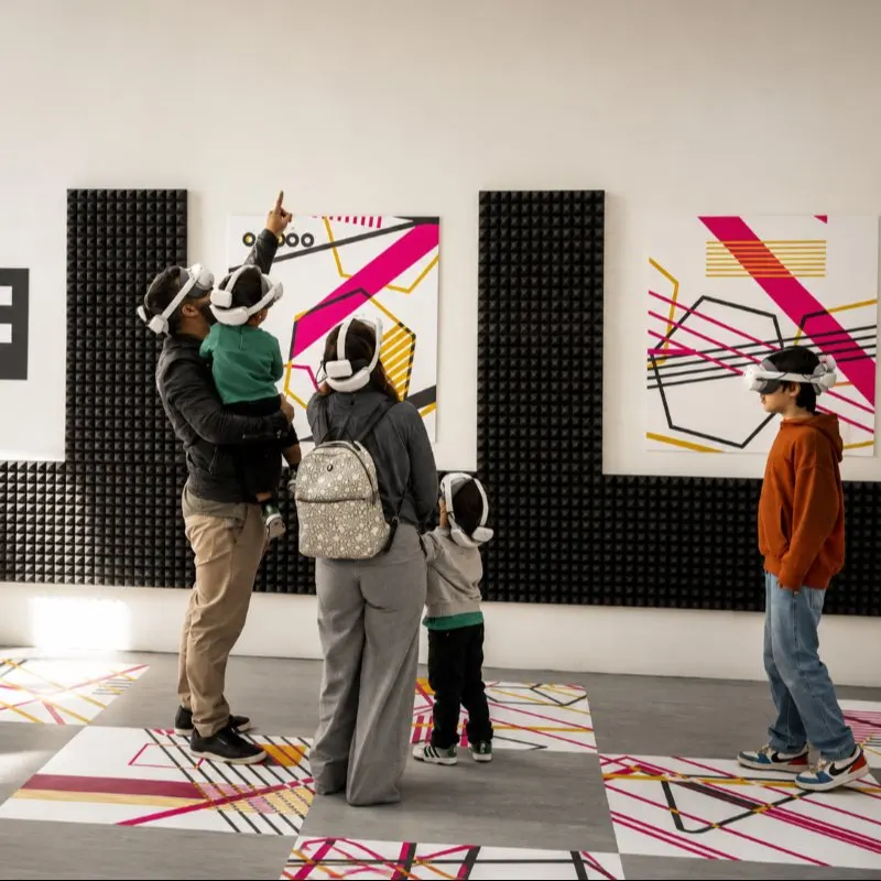 A family wearing virtual reality headsets in a white room with patterned floor and walls, during the metaverse part of Porto Legends